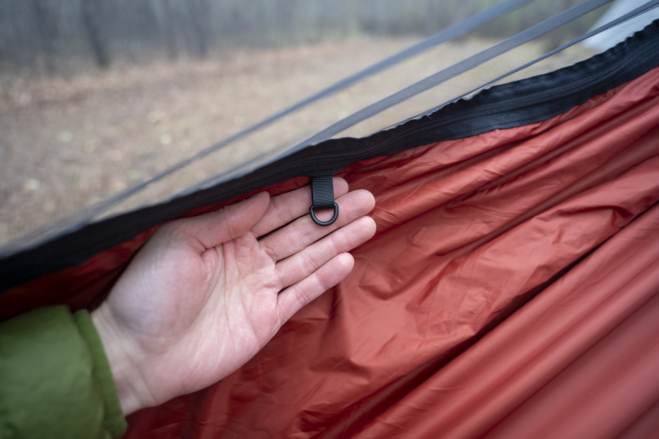 a hand holds a d ring attached to the interior of a hammock