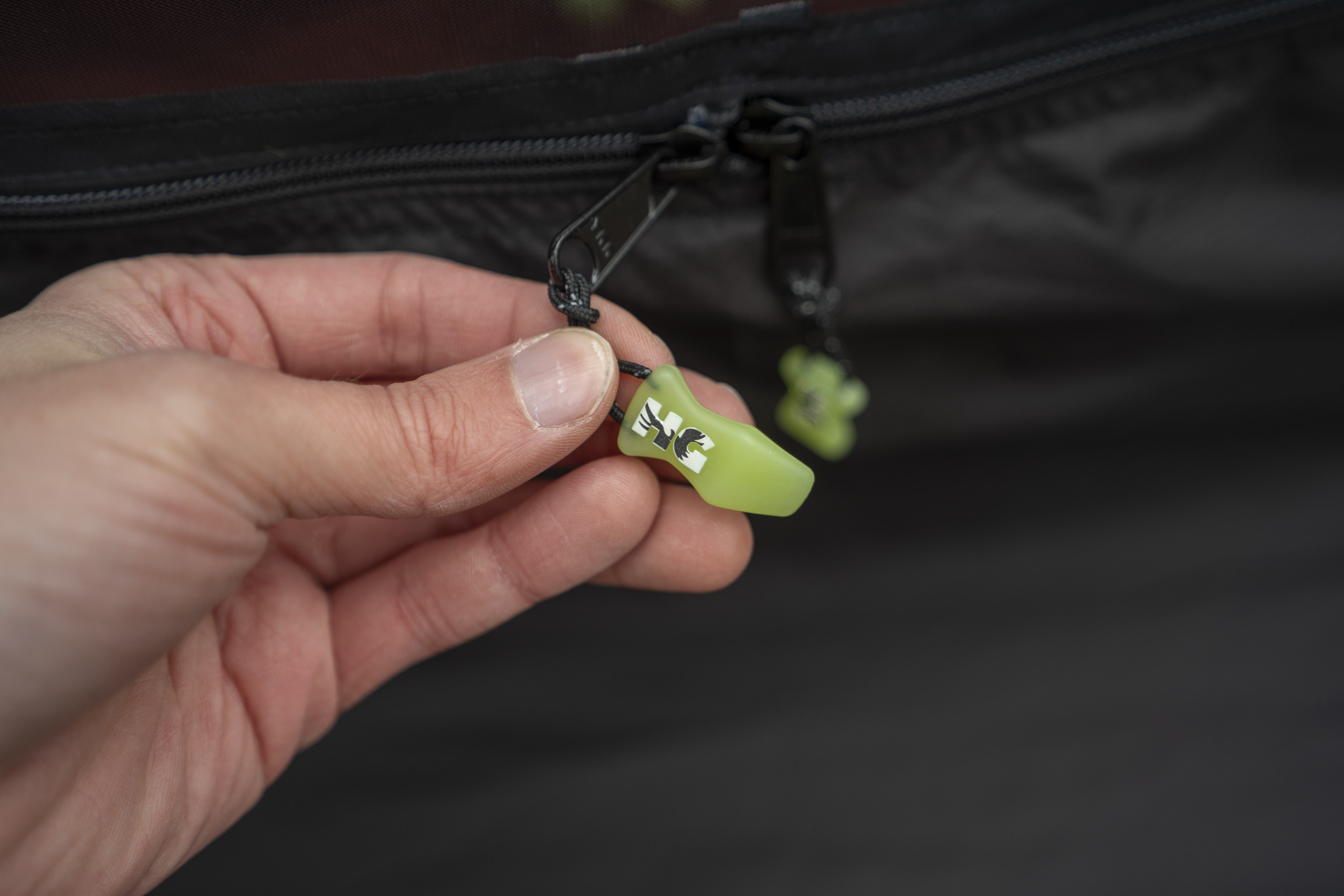 a hand holds glow in the dark zipper pulls on a hammock