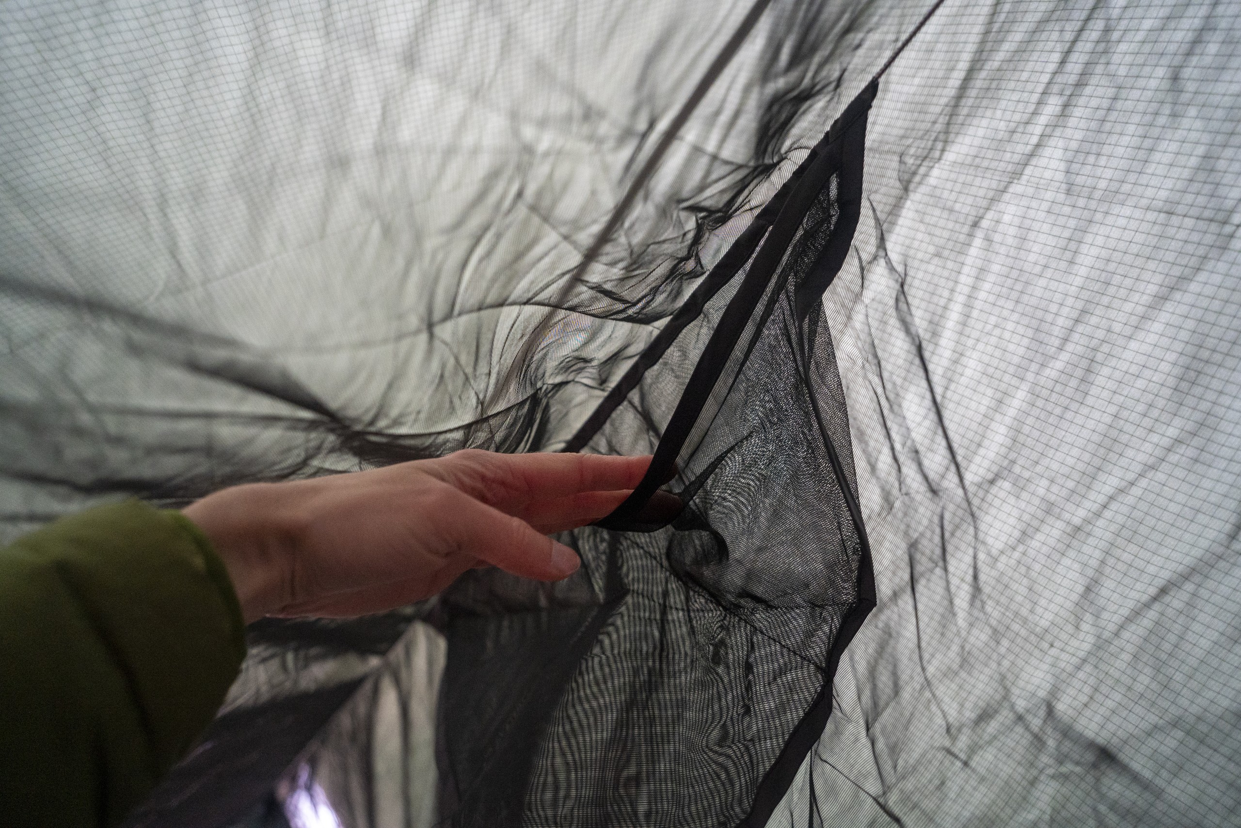 a hand holds open a pocket on the ridgeline of a hammock