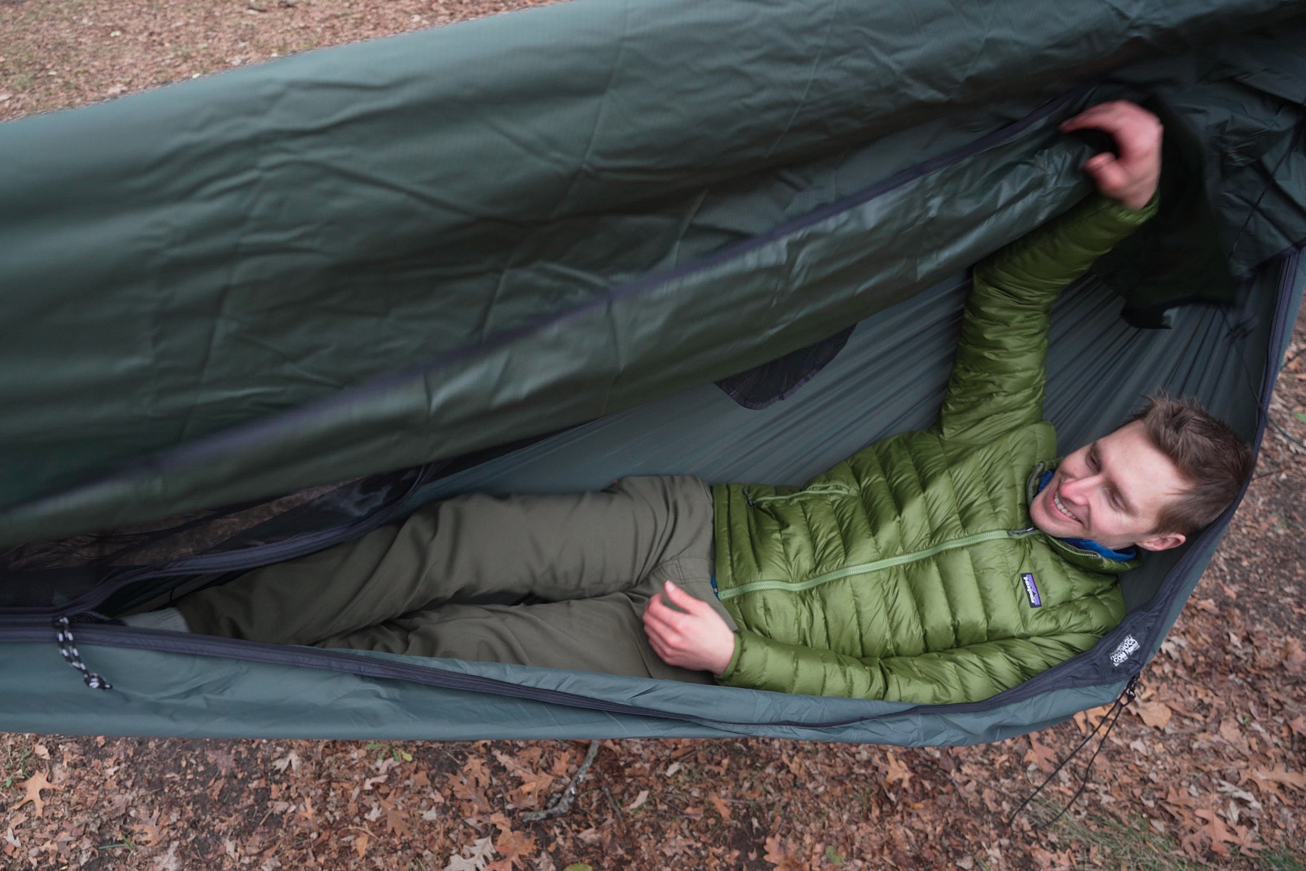 a man in a green jacket lies in a green hammock