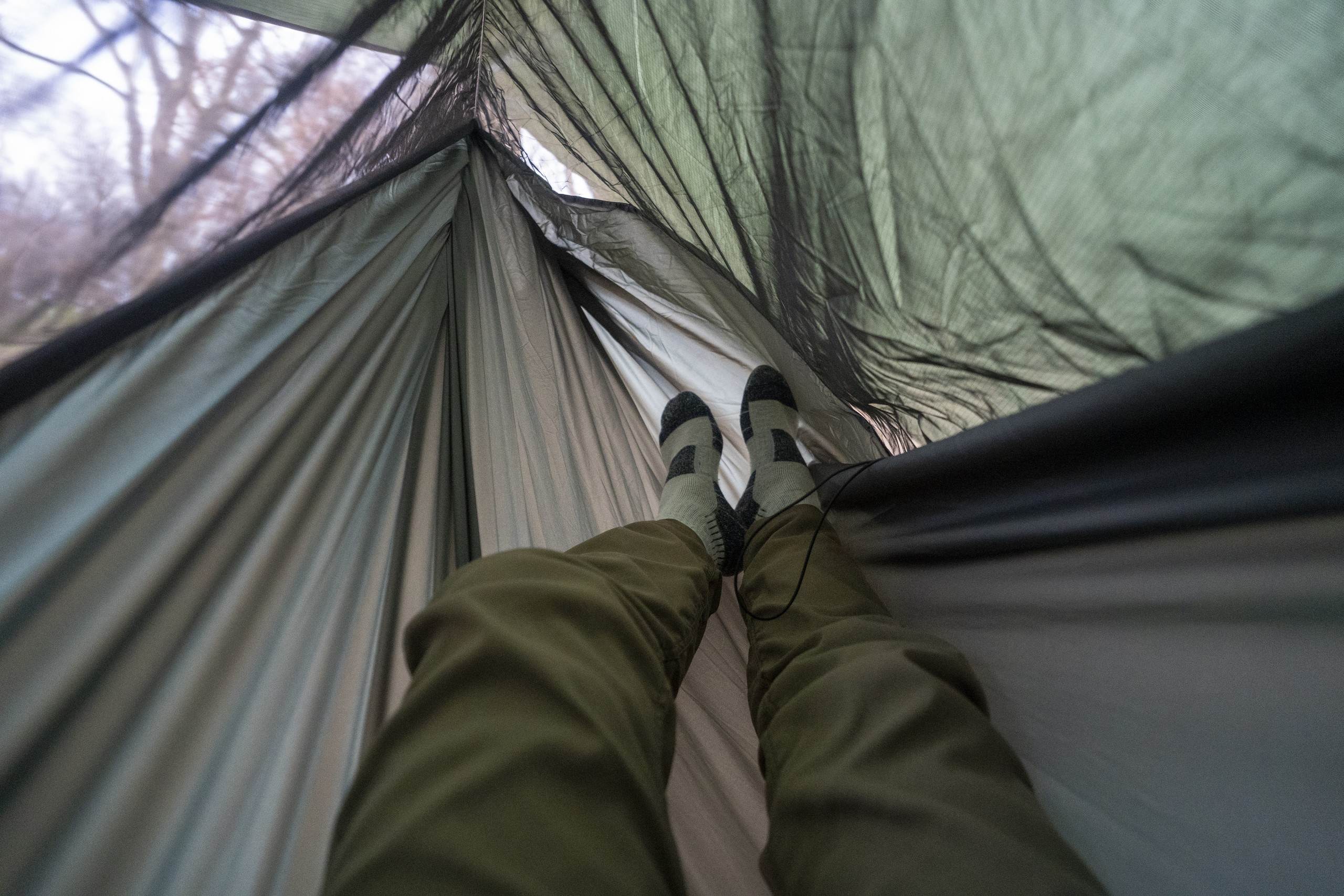 a pair of legs extend into a hammock from a point of view perspective