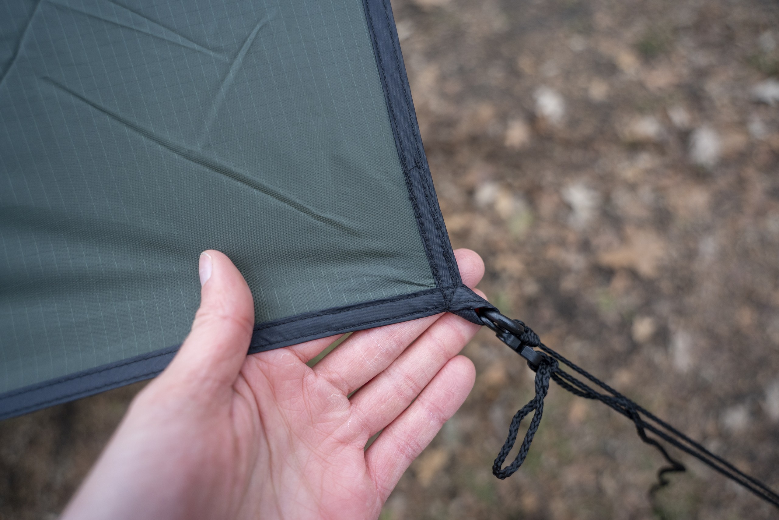 a hand holds a corner of a tarp