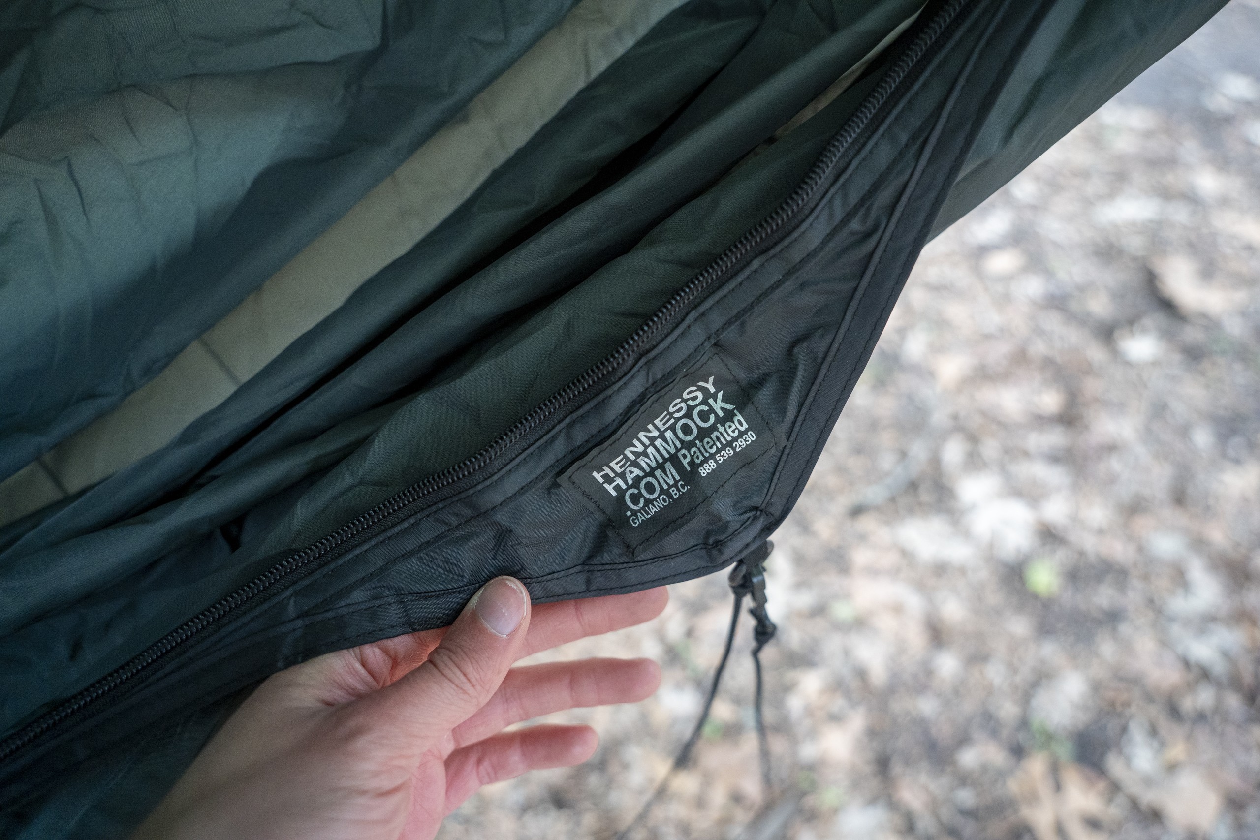 a hand holds a hammock that displays a logo