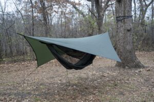 a green hammock with a green tarp in a forest clearing