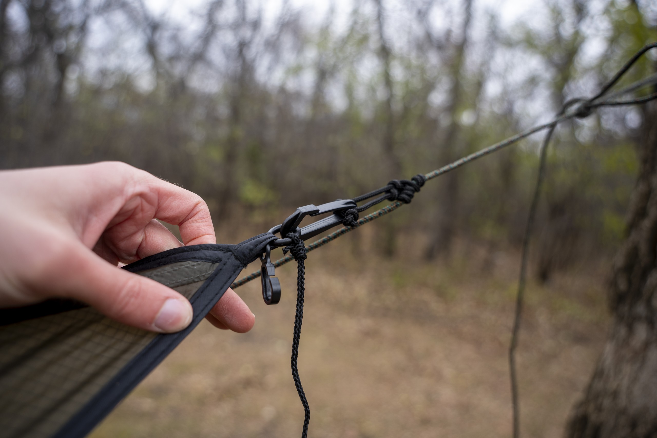 a hand holds a tarp end connected to a cord