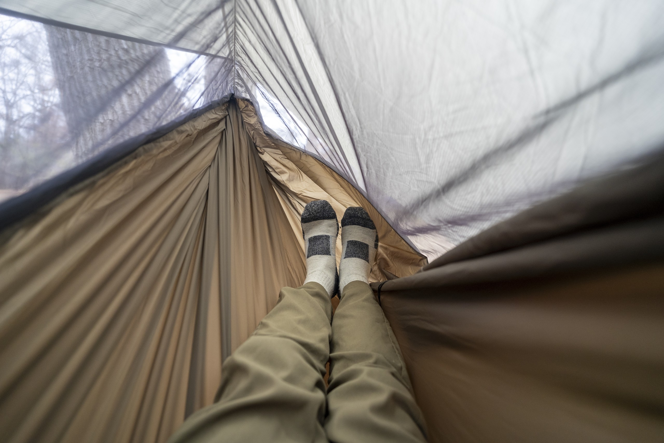 a pair of legs extend into a hammock from a point of view perspective