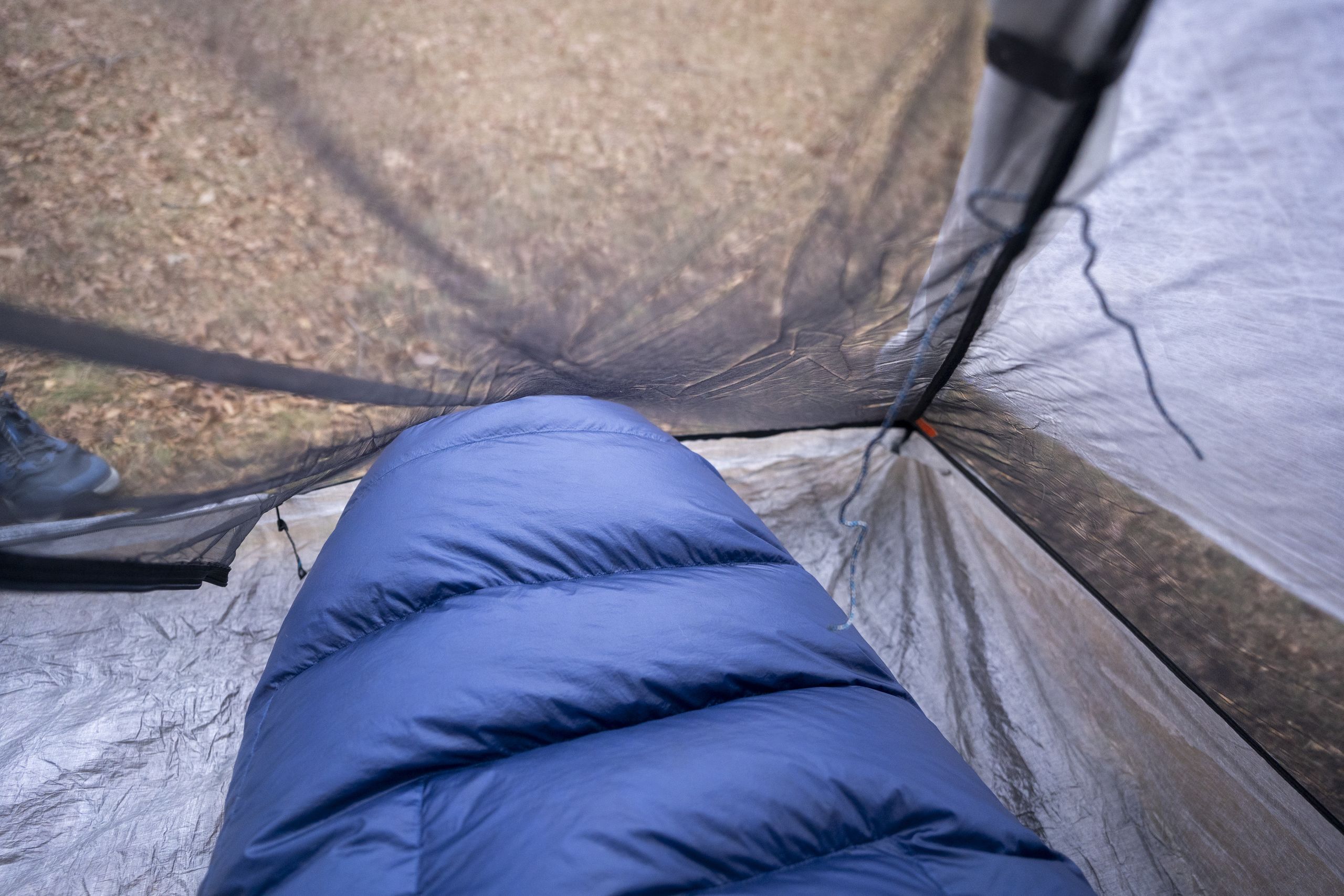 a sleeping bag touches the mesh of a tent