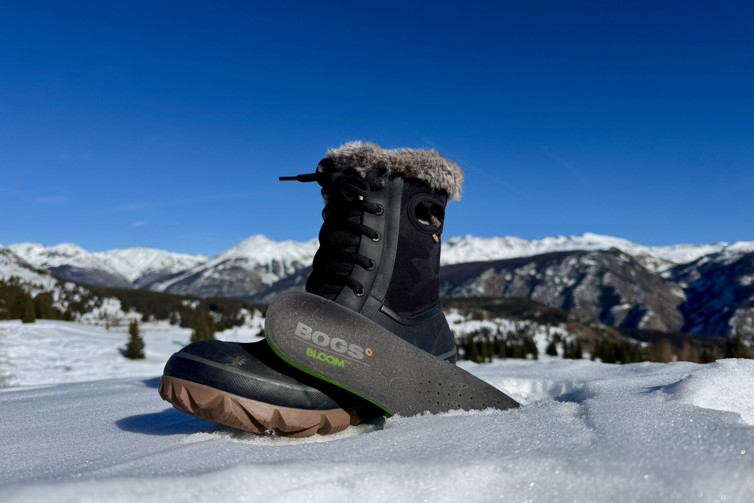 A close up of the Bogs Arcata boot with the insole sitting next to it. They are set on some snow in the mountains.