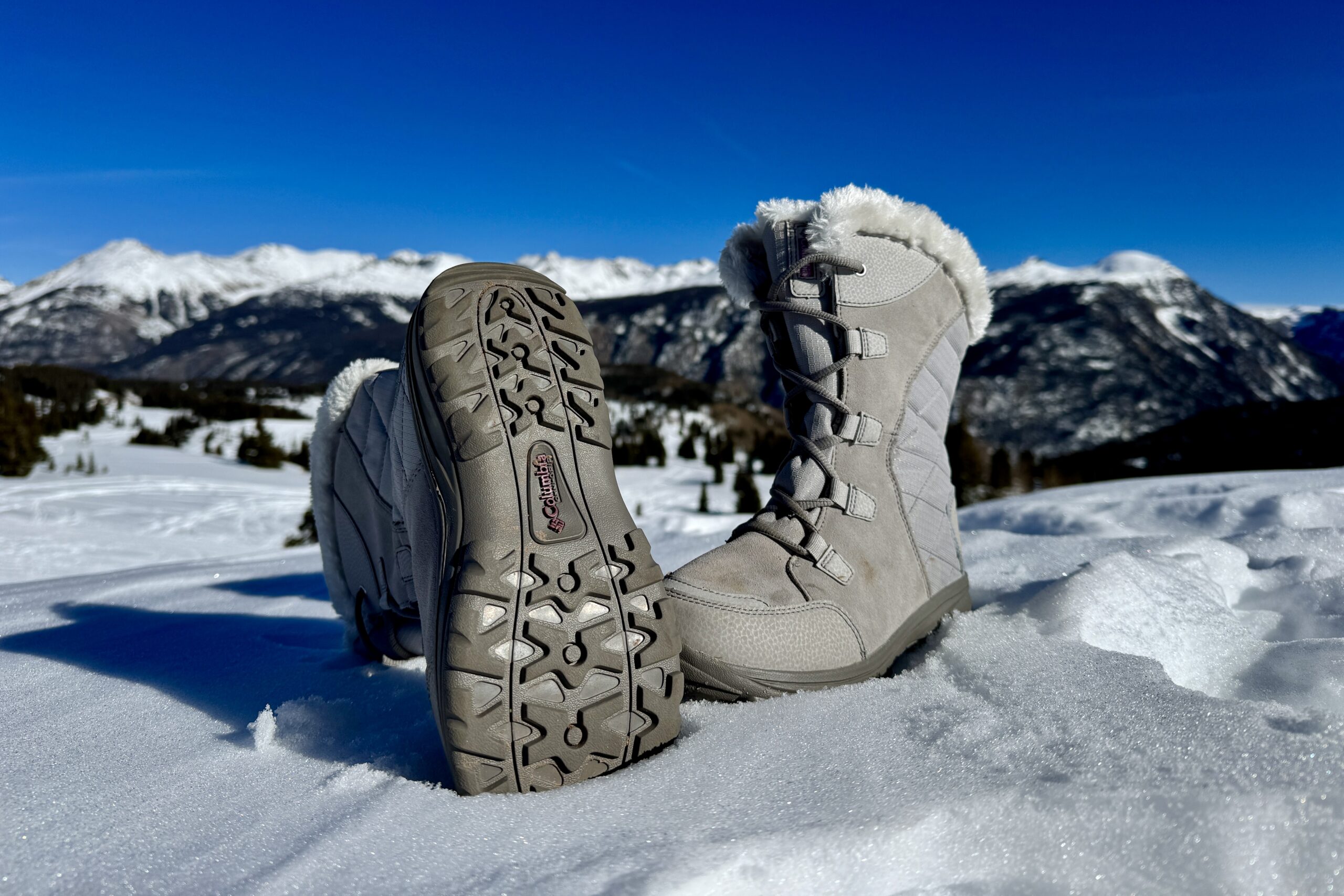 A close up of the tread on the bottom of the Ice Maiden boot. It is sitting in the snow in the mountains.