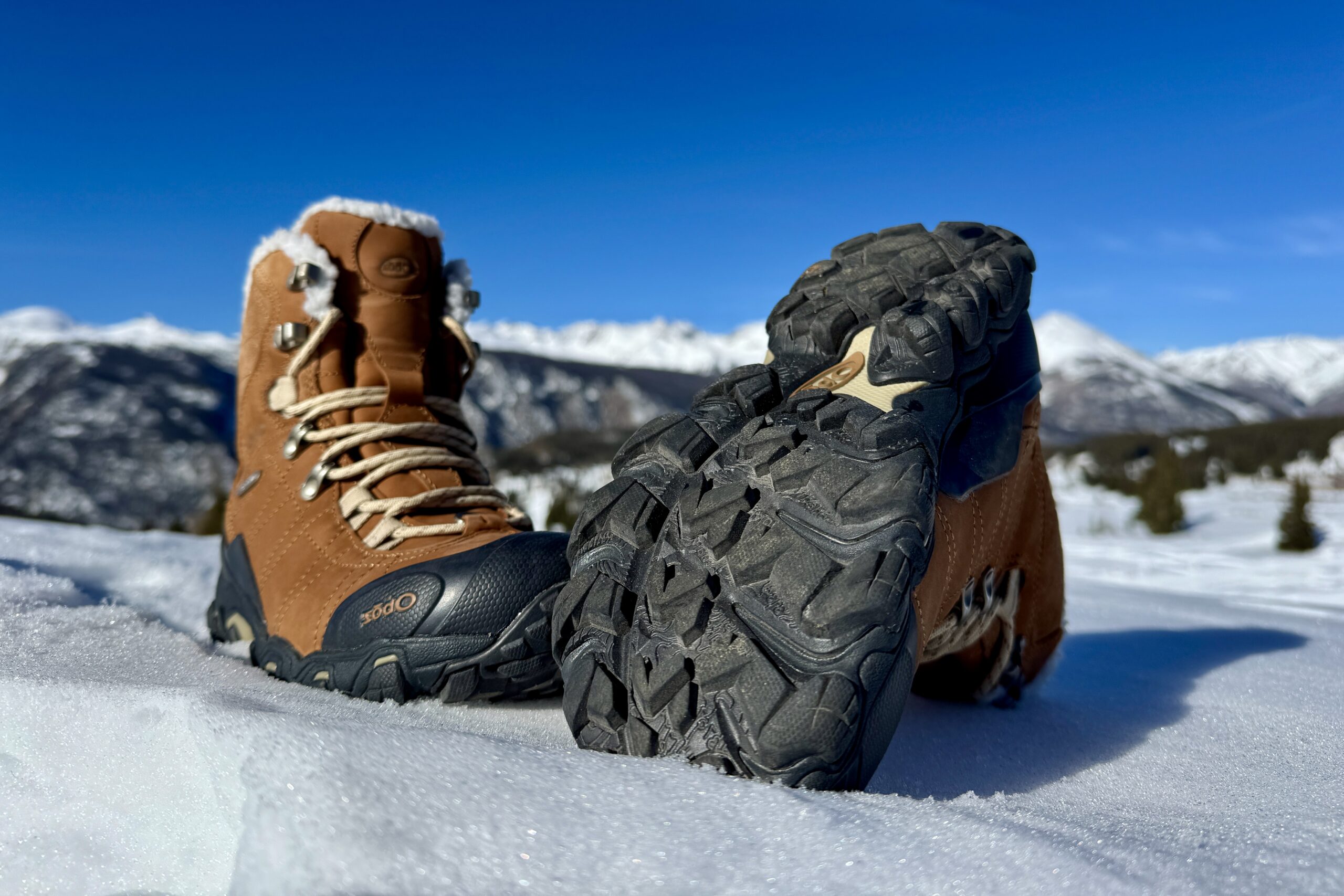 A close up of the tread on the bottom of the Oboz boot. It is sitting in the snow in the mountains.