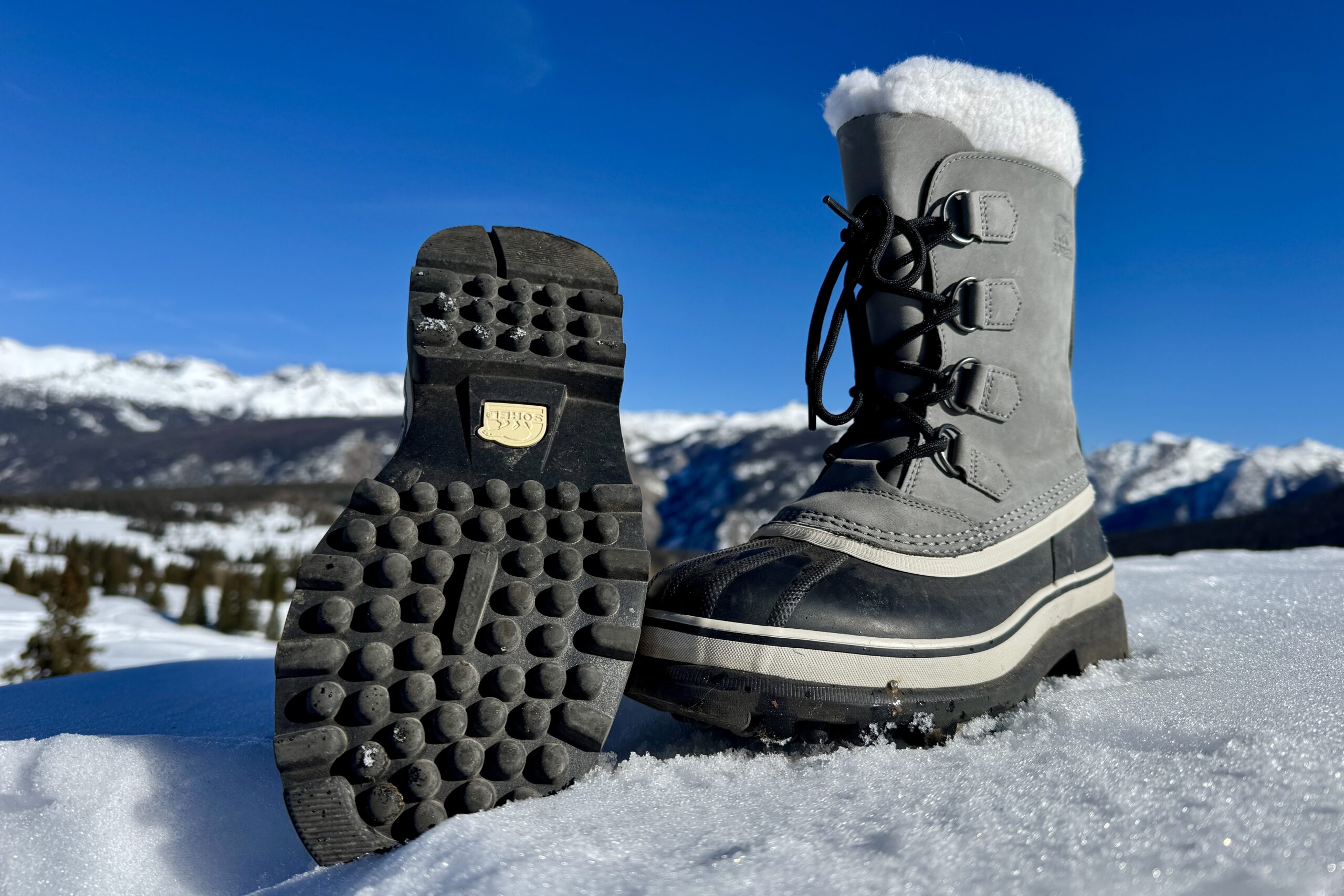 A close up of the tread on the bottom of the Sorel boot. It is sitting in the snow in the mountains.