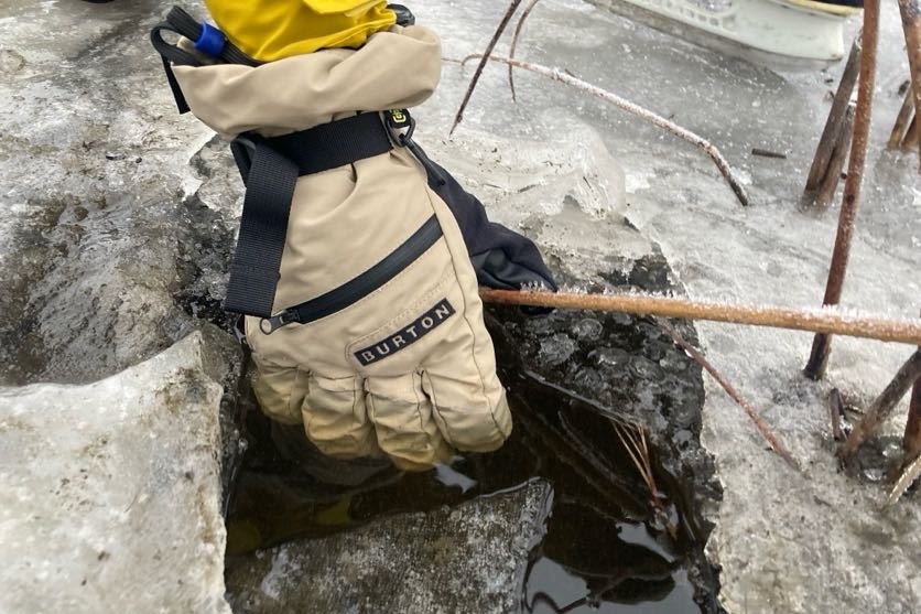 A man submerges a winter glove in water.