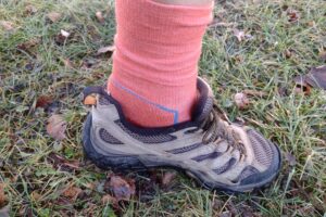 Closeup of someone wearing the light red colored Icebreaker Hike + Light socks in tan hiking shoes.