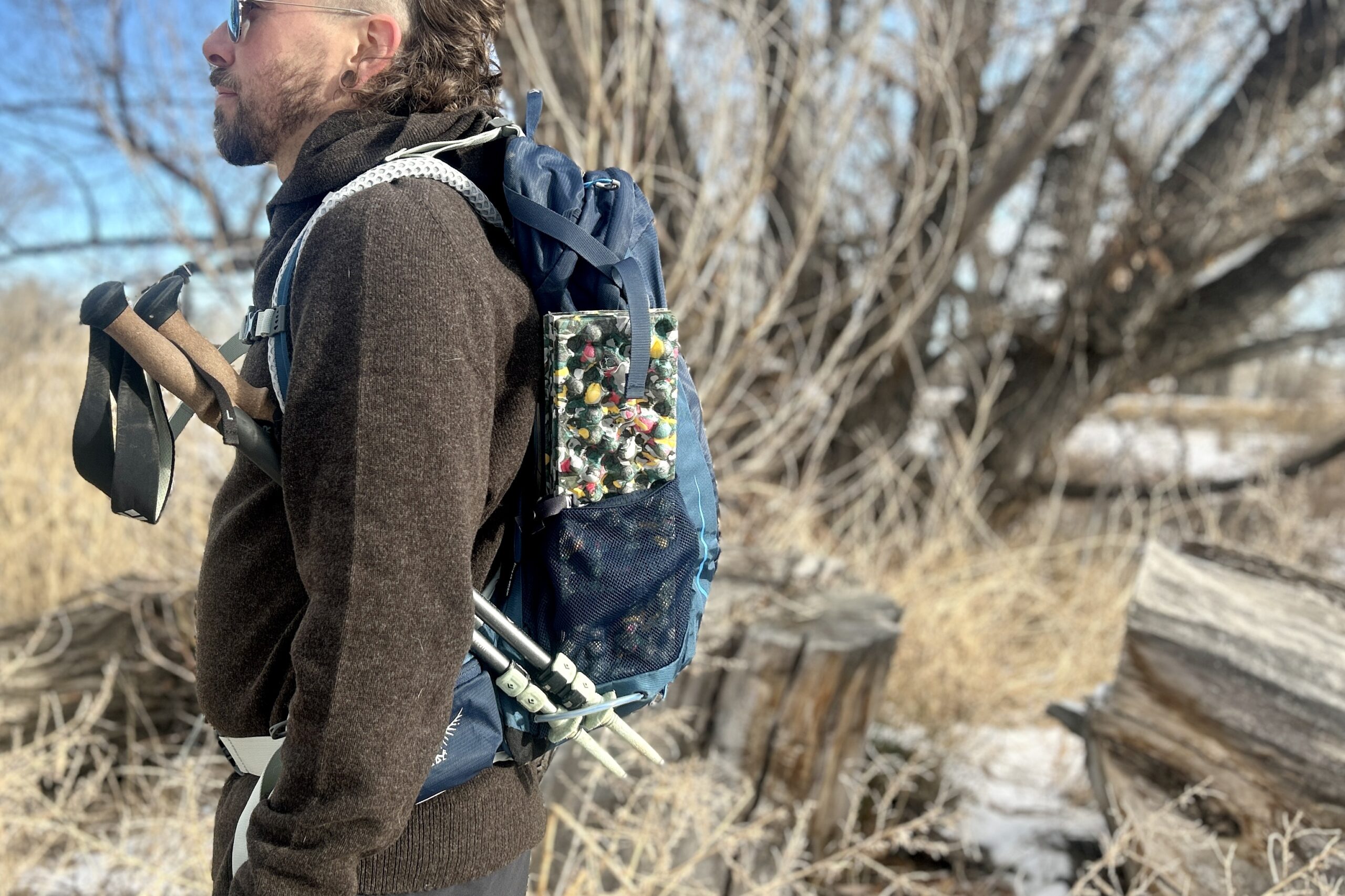 Close up of a person wearing a backpack from the side in a forest setting.