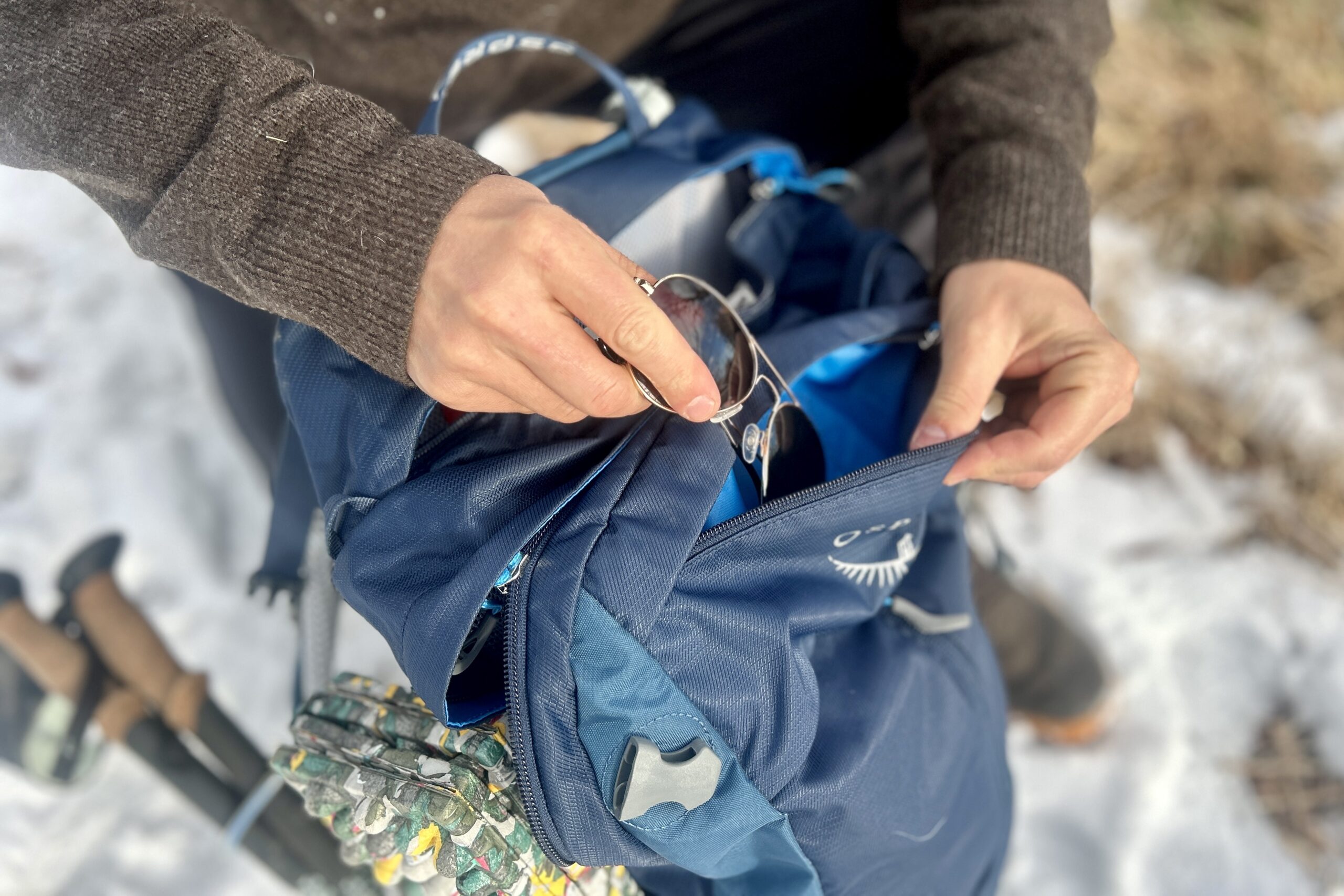 Close up of a person pulling out the contents of their backpack from a pocket.