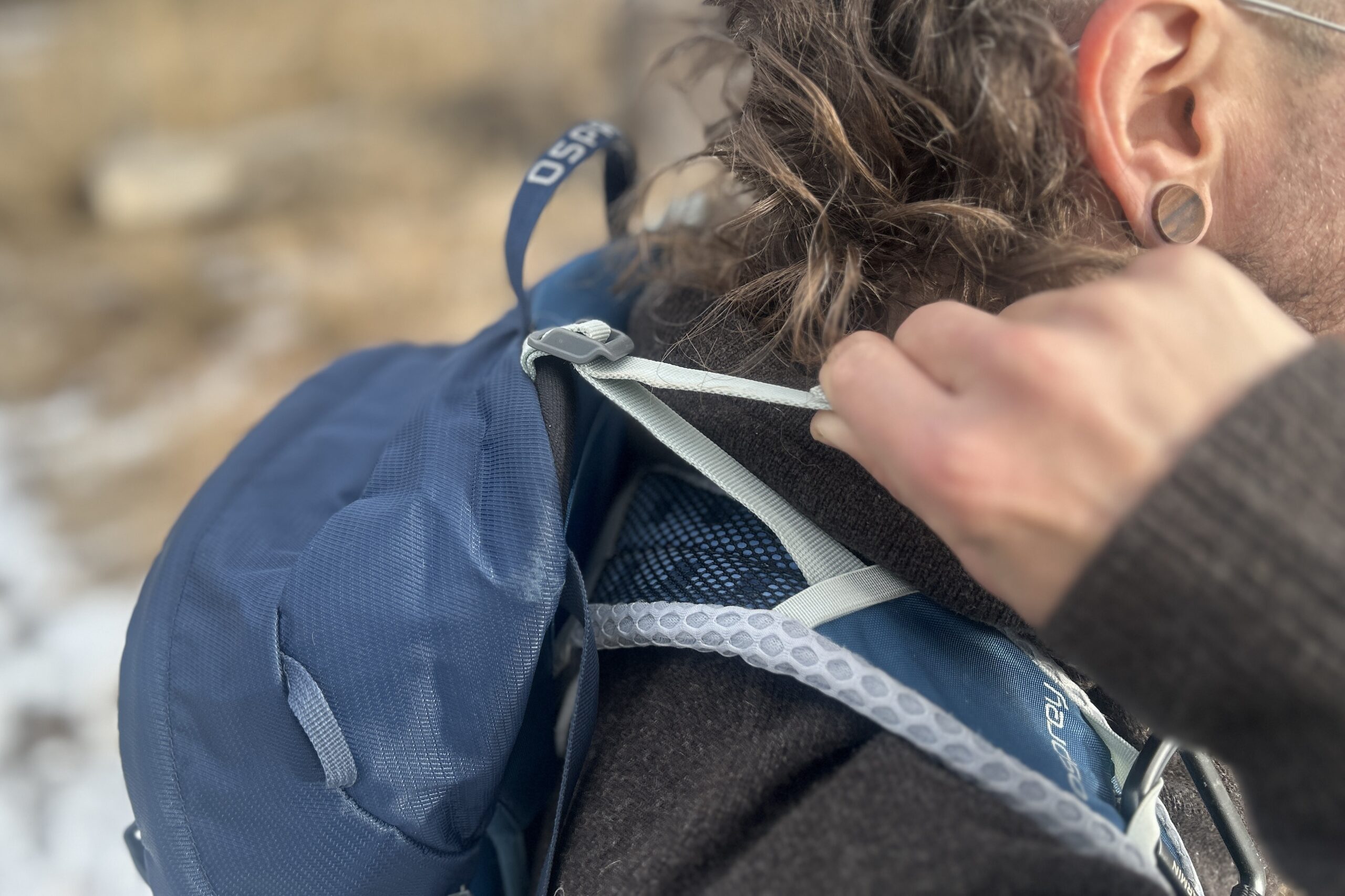 Close-up shot of a person tightening their load lifters on a backpack.