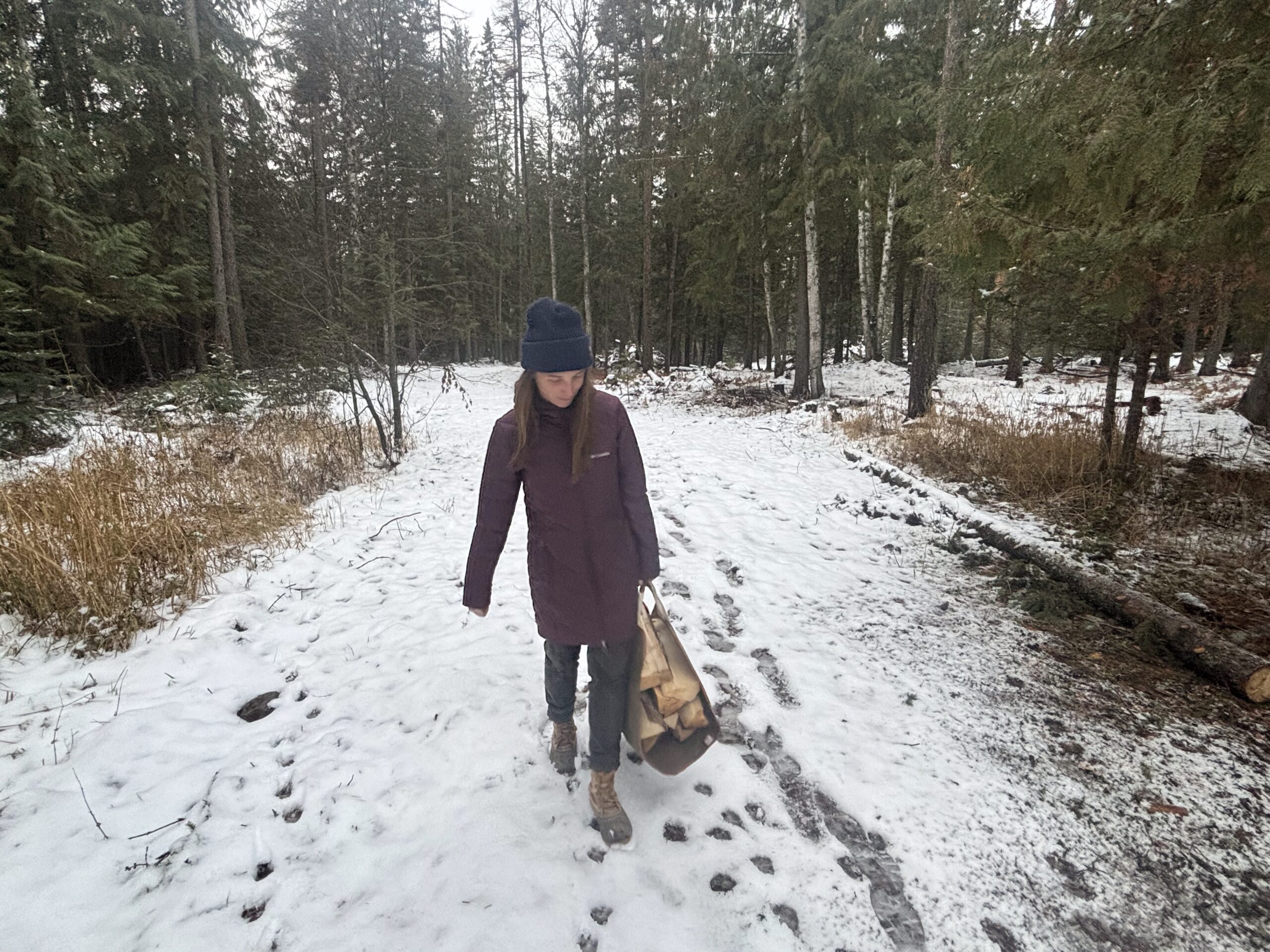 a woman carrying a load of firewood while wearing the columbia heavenly