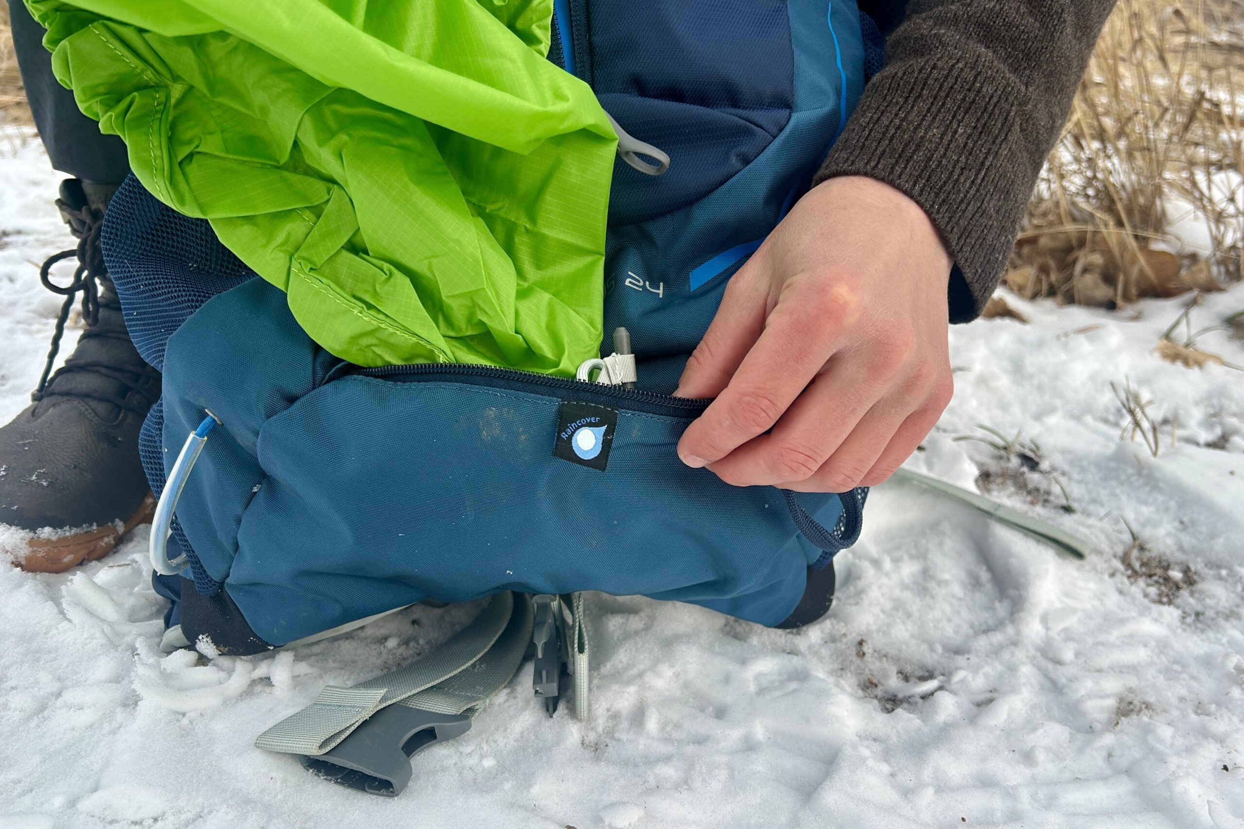 Close up of a person pulling out the rainfly from the bottom of their daypack.