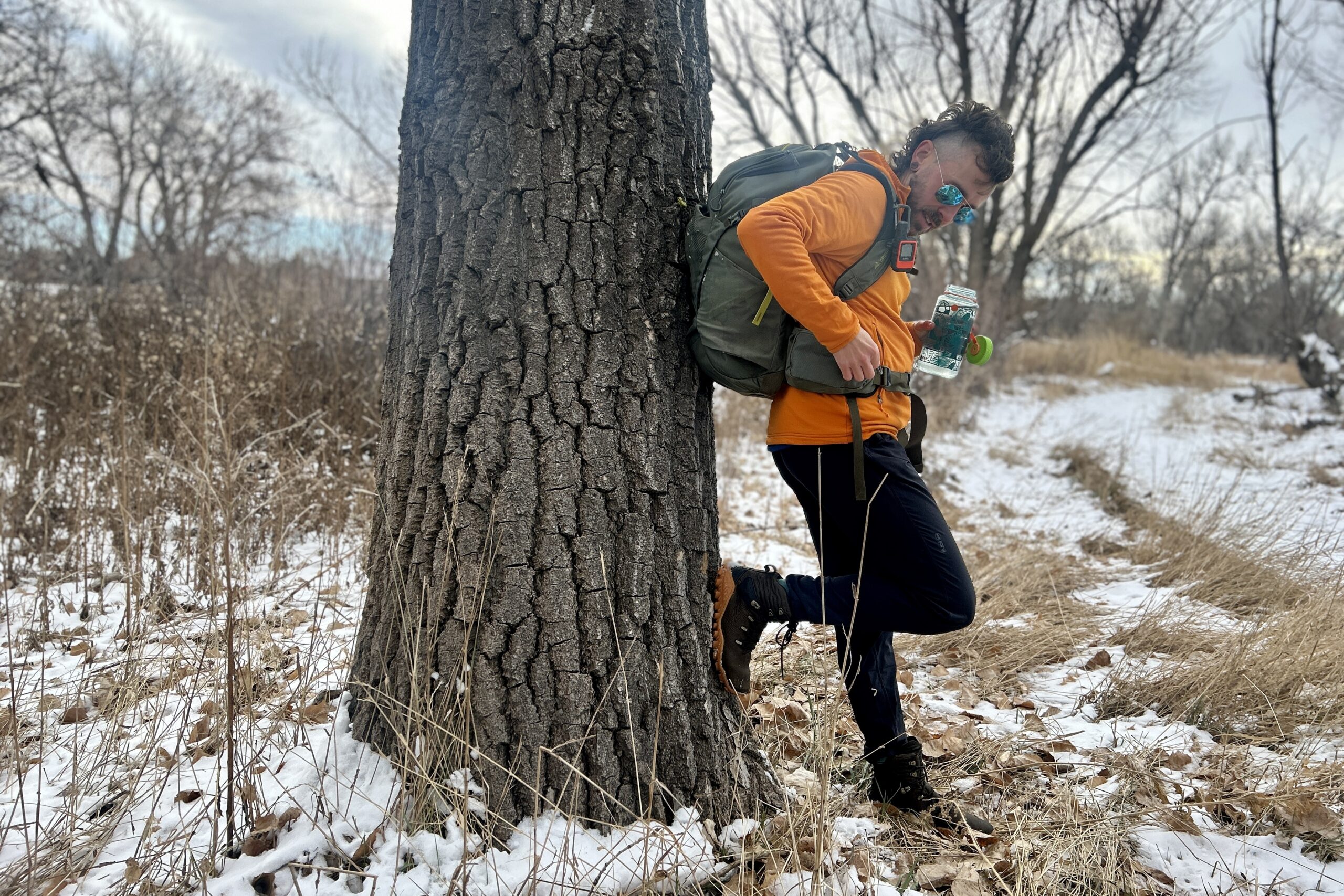 A man poses with a big backpack on in a snowy wilderness area.