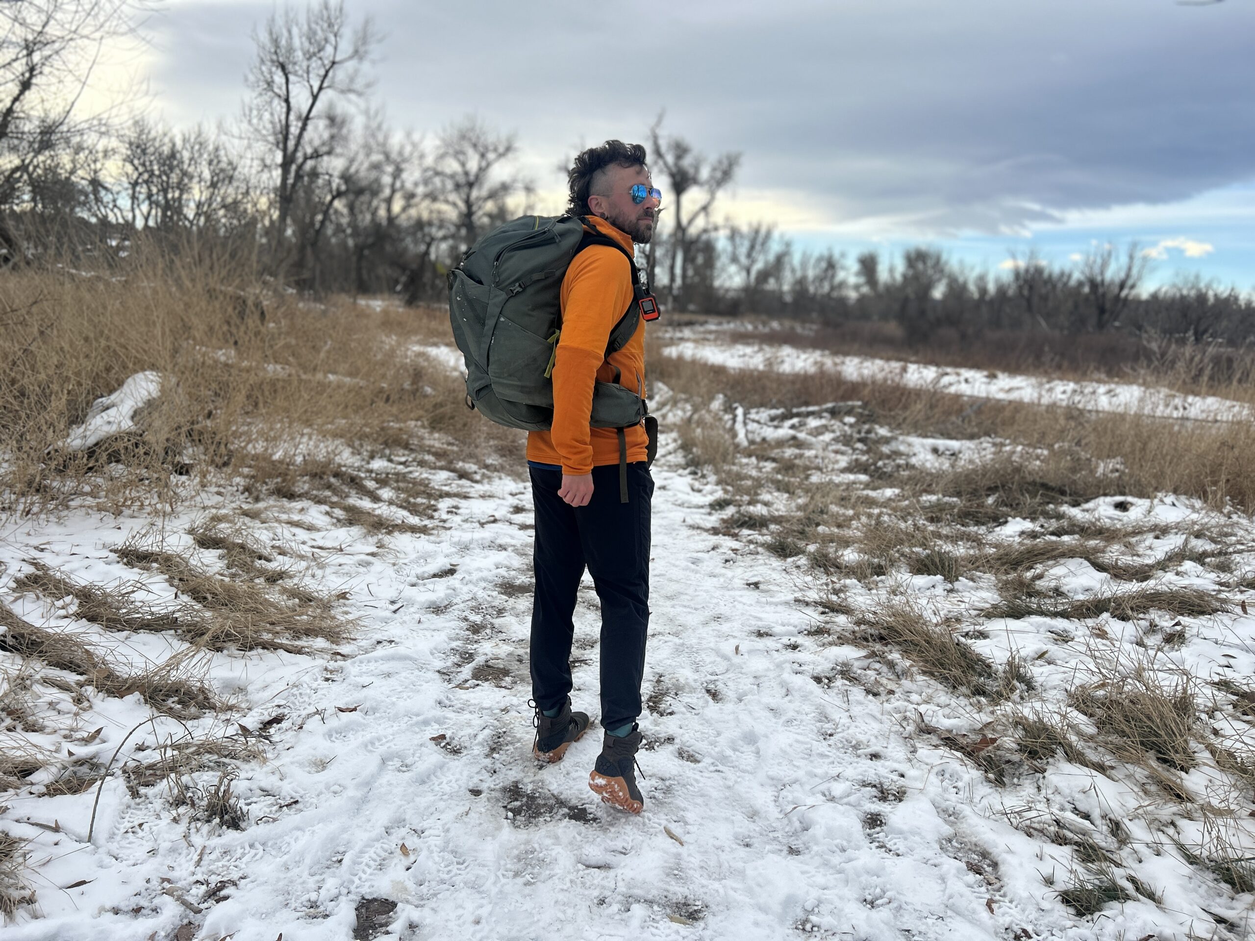 A man poses with a big backpack on in a snowy wilderness area.