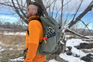 Close up of a man wearing a large daypack from the side.