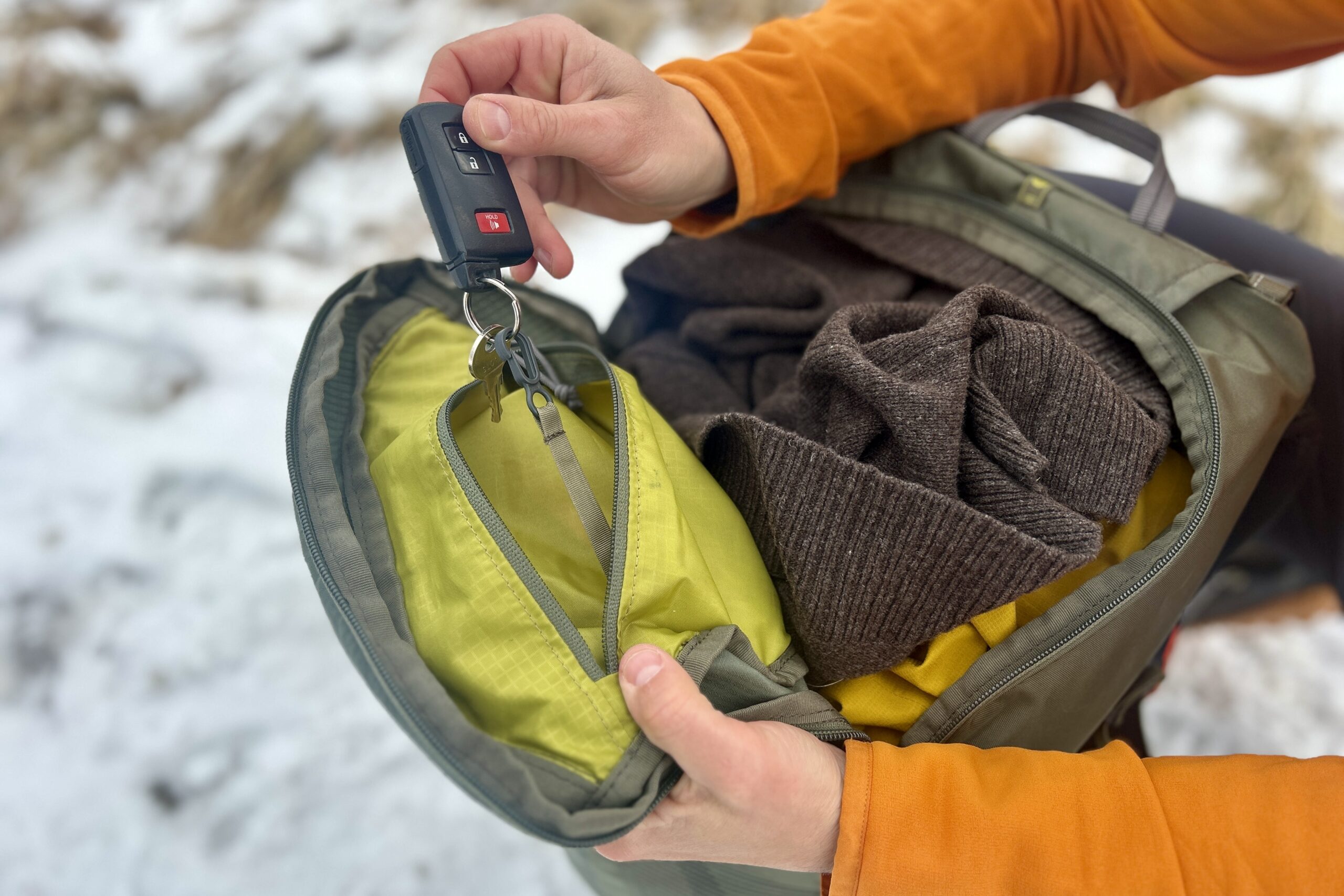 Close up of a person digging through the pockets of their backpack.