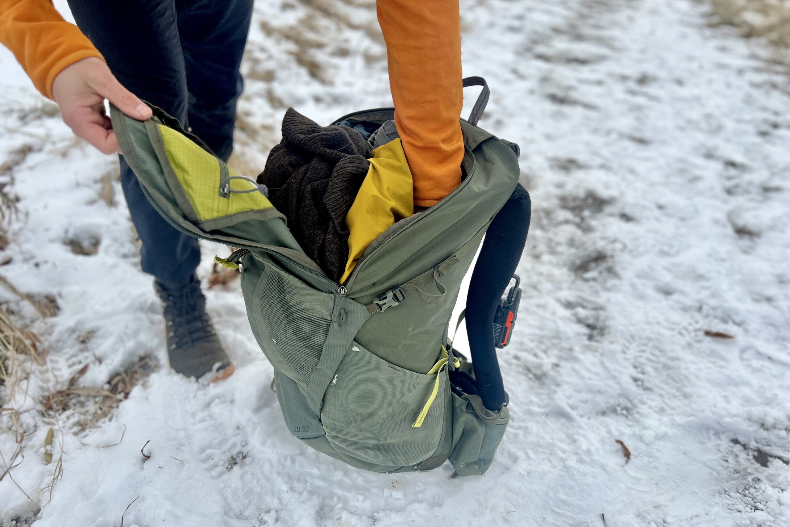 Close up of a person digging through the pockets of their backpack.