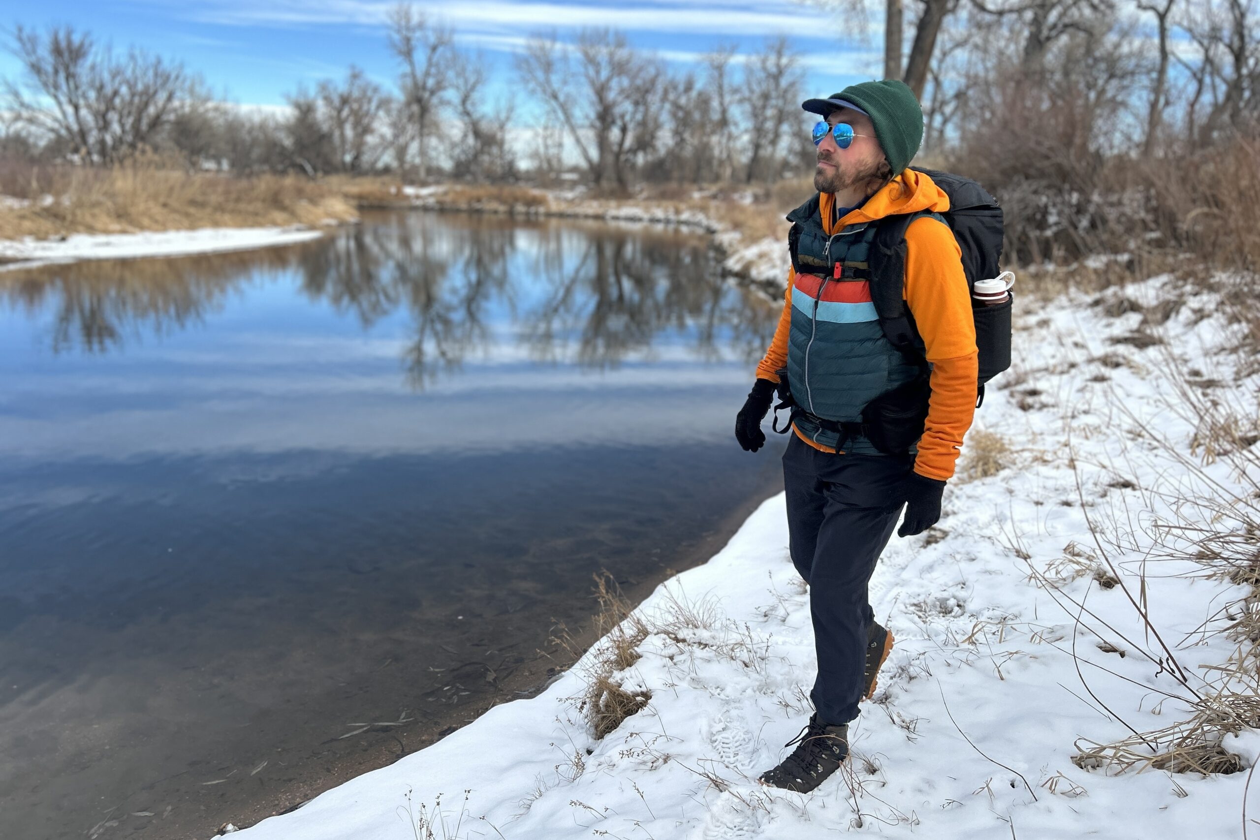 A man hikes in a snowy wilderness area with a large backpack on.