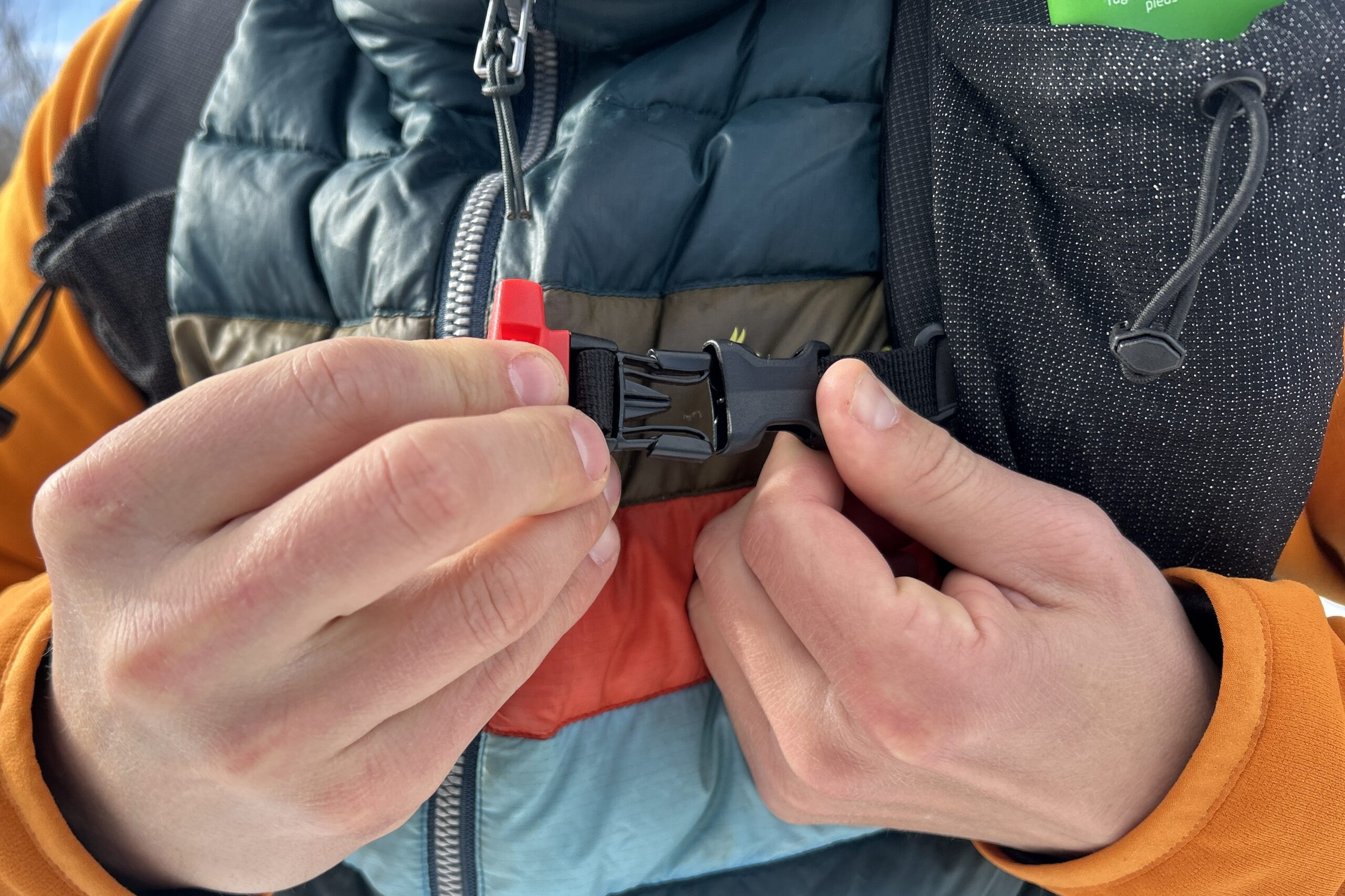 Close up image of a person buckling a buckle on their backpack.