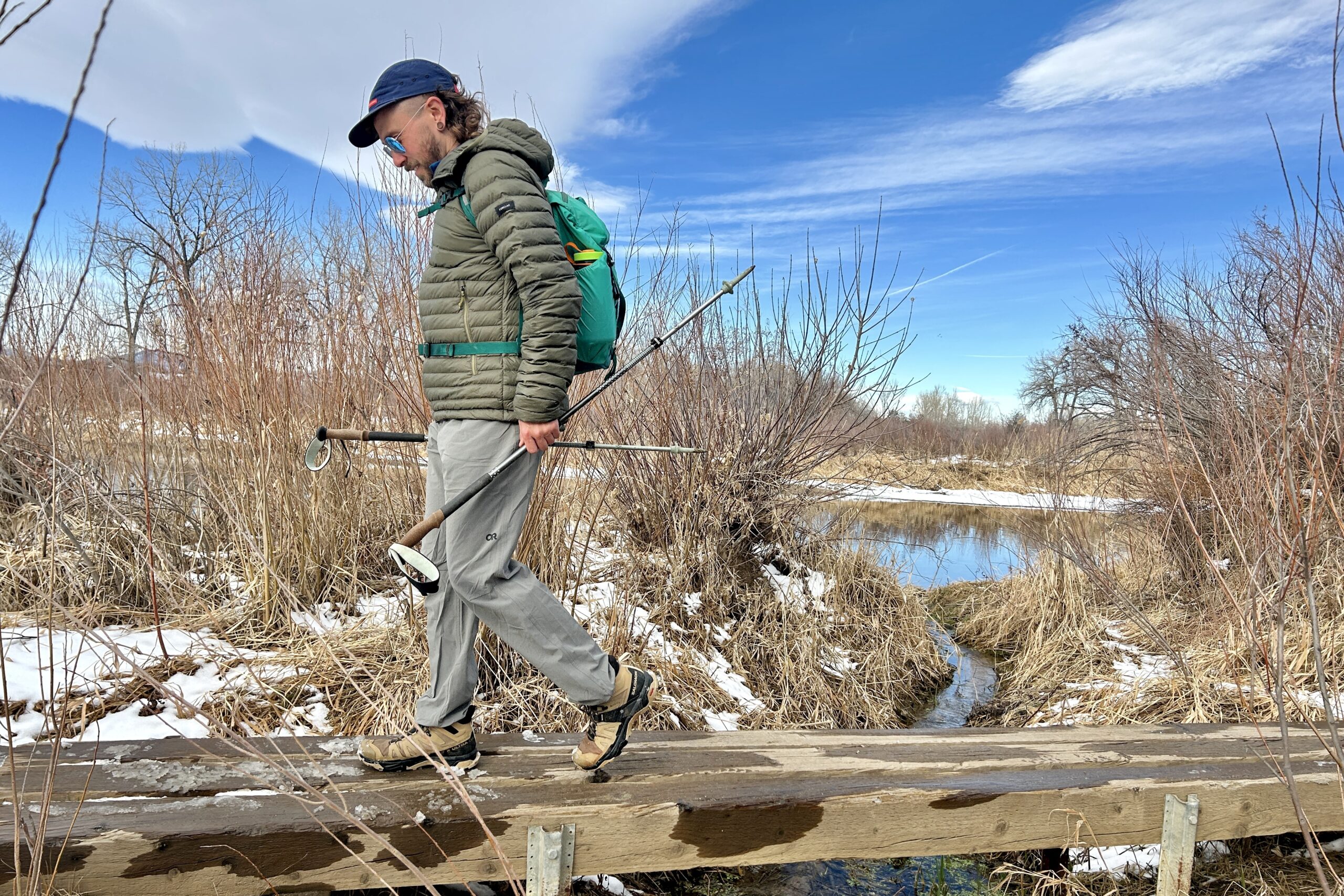 A man hiking over a wooden bridge in a wilderness area.