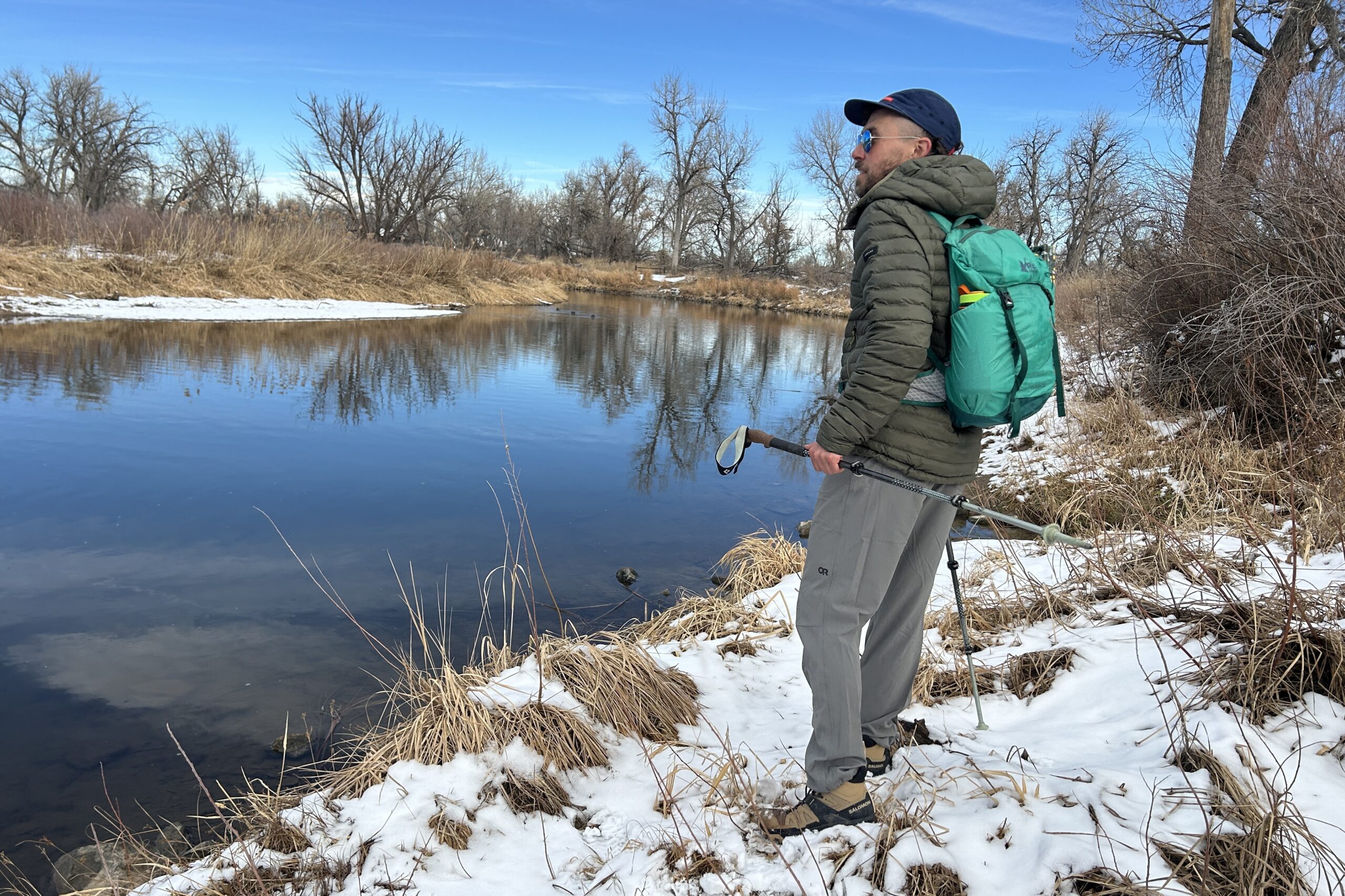 A man hiking next to a river in a snowy wilderness area.