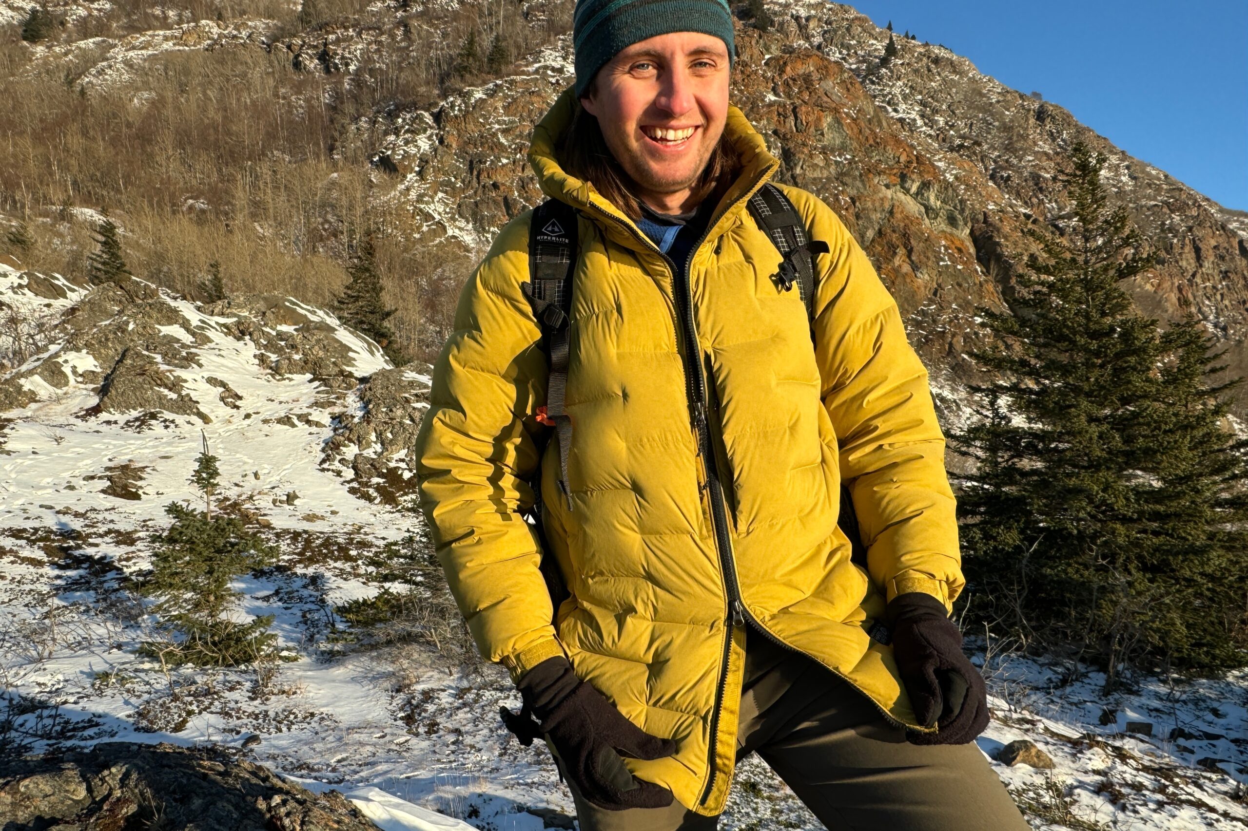 A man unzips his yellow down jacket.