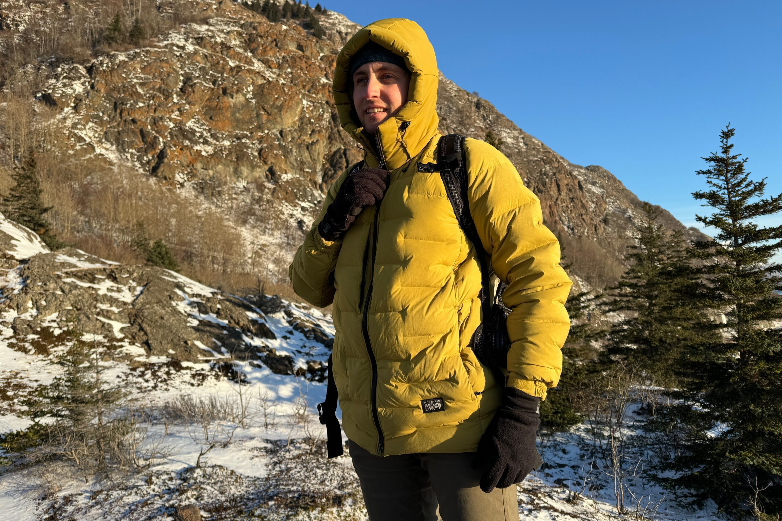 A man zips up the hood of his yellow down jacket.