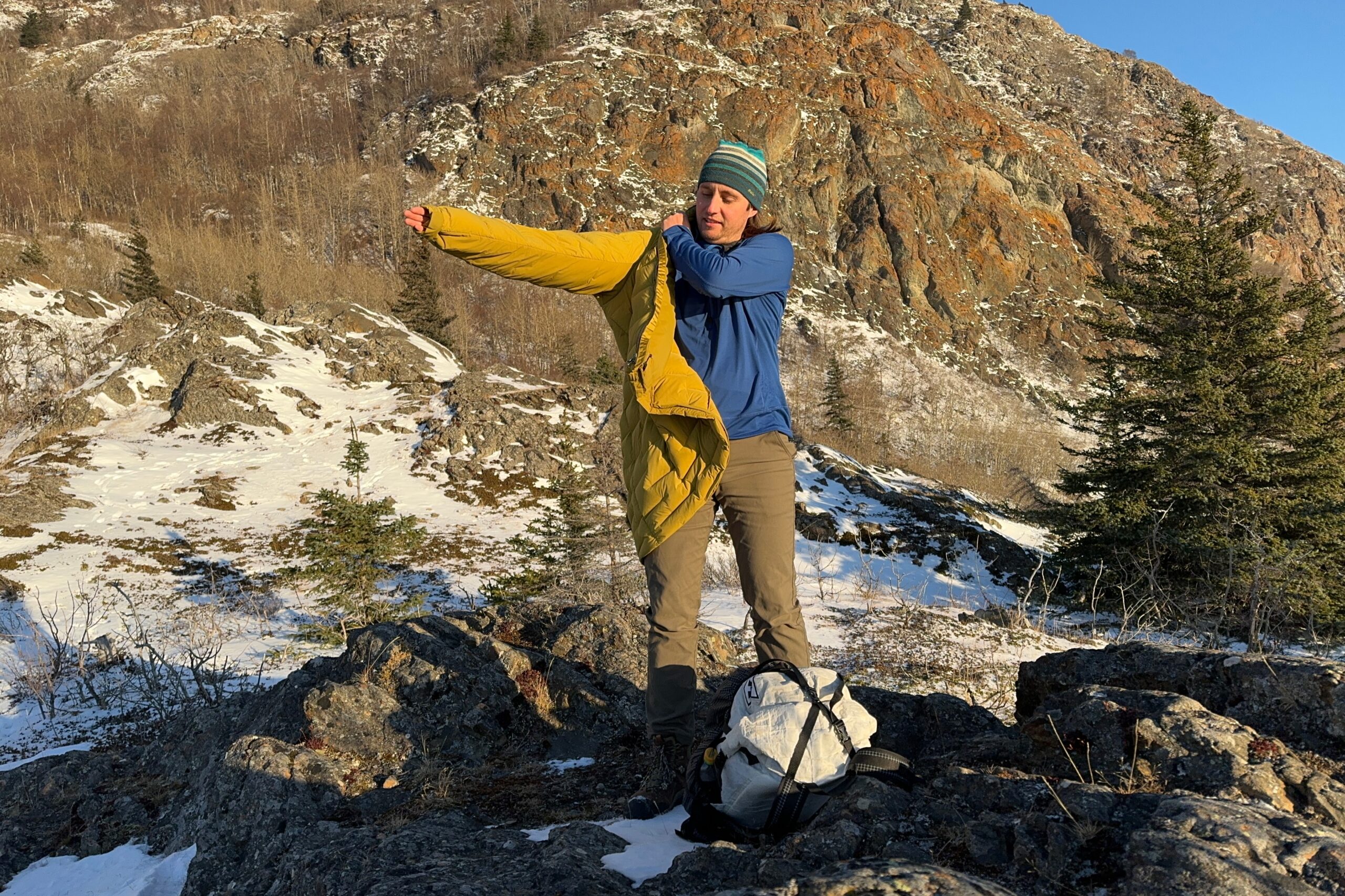 A man puts on a yellow down jacket.