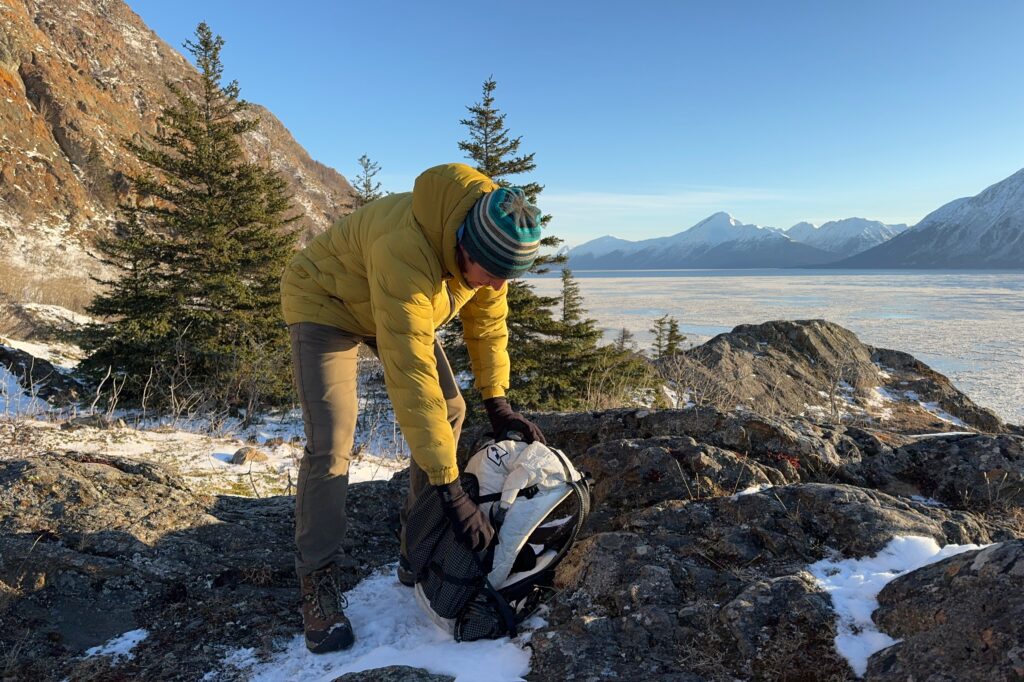 A man retrieves his water bottle from his backpack on a winter day.