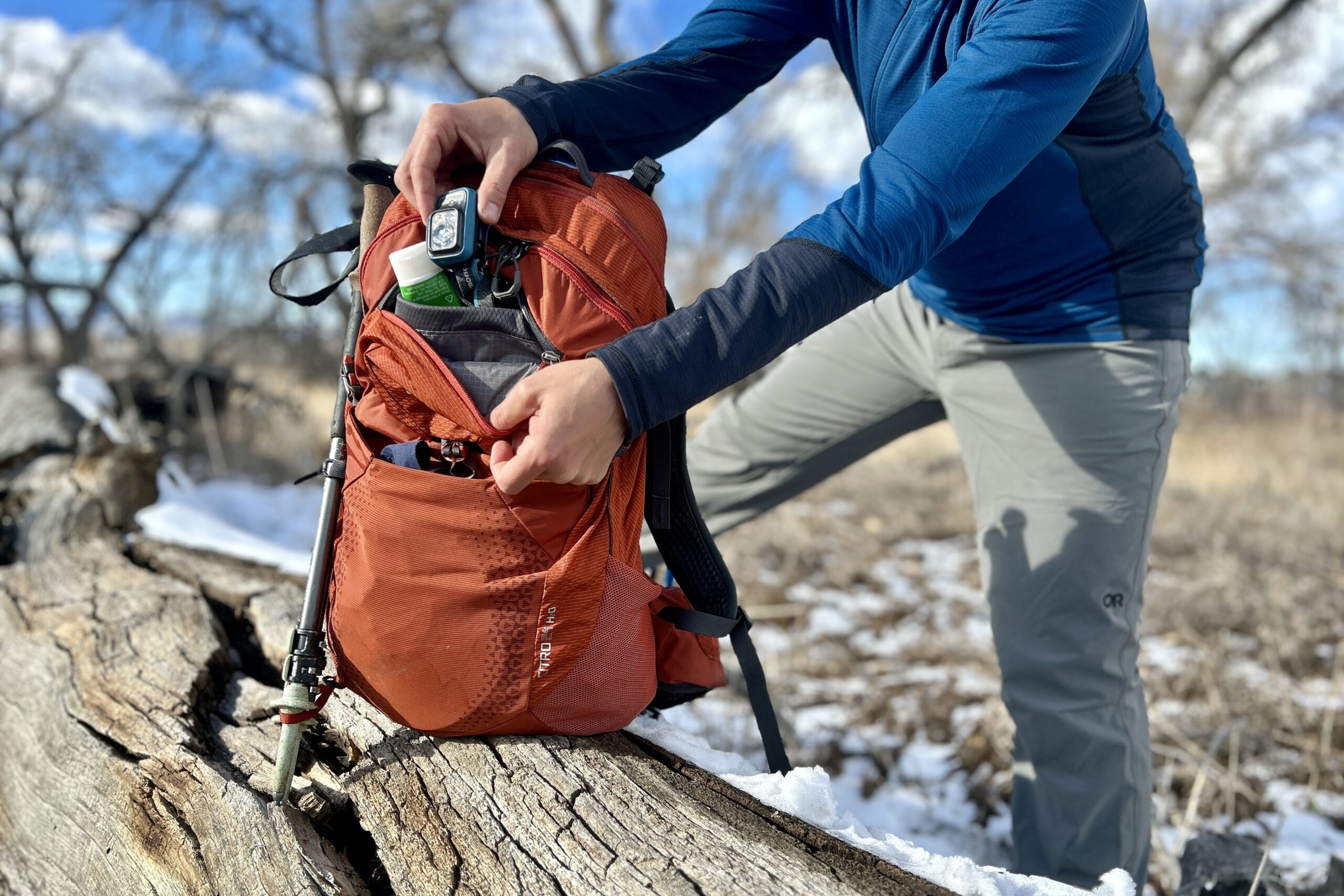 A person digs through the gear in the front pocket of their backpack.