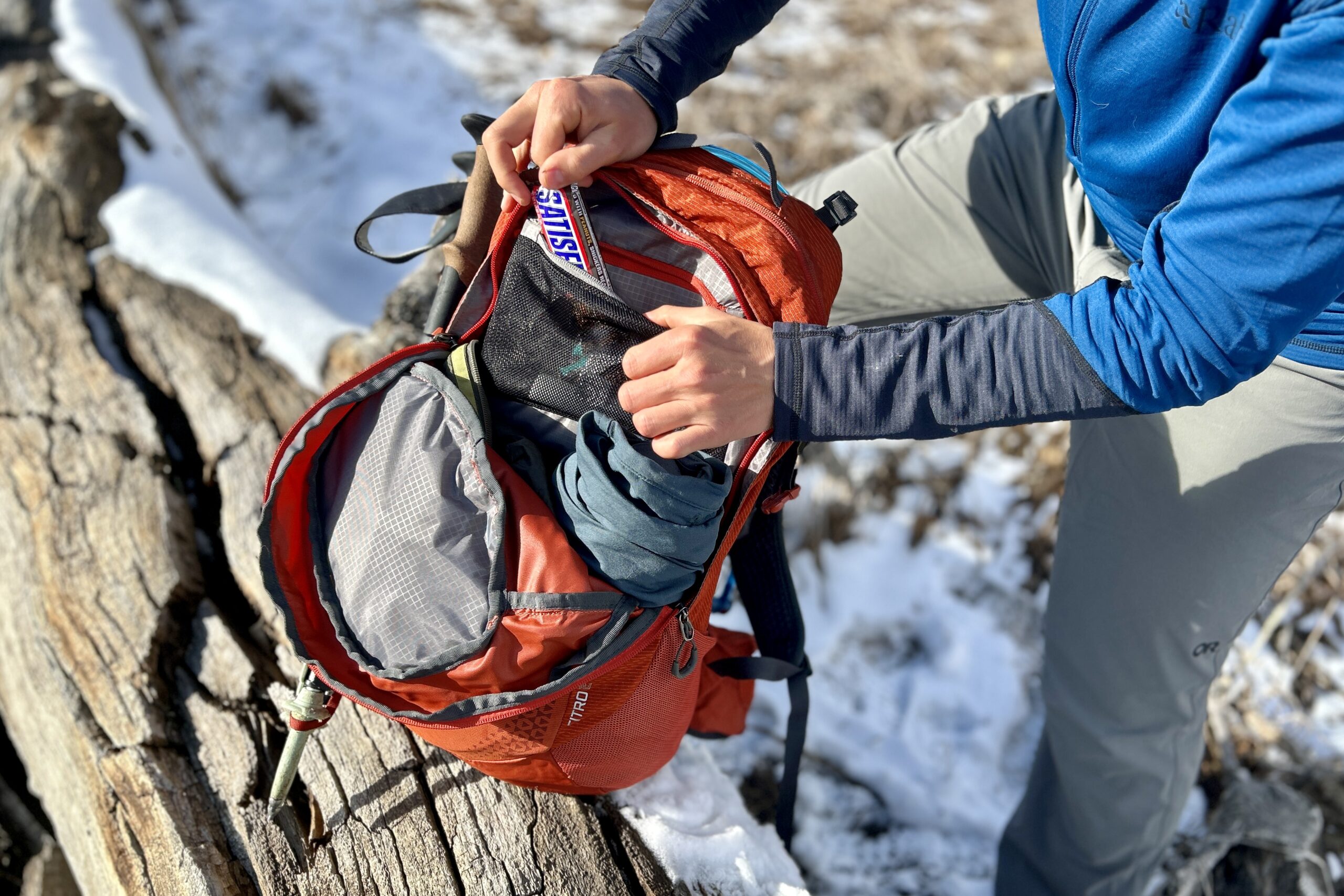 A person digs through the gear in the front pocket of their backpack.