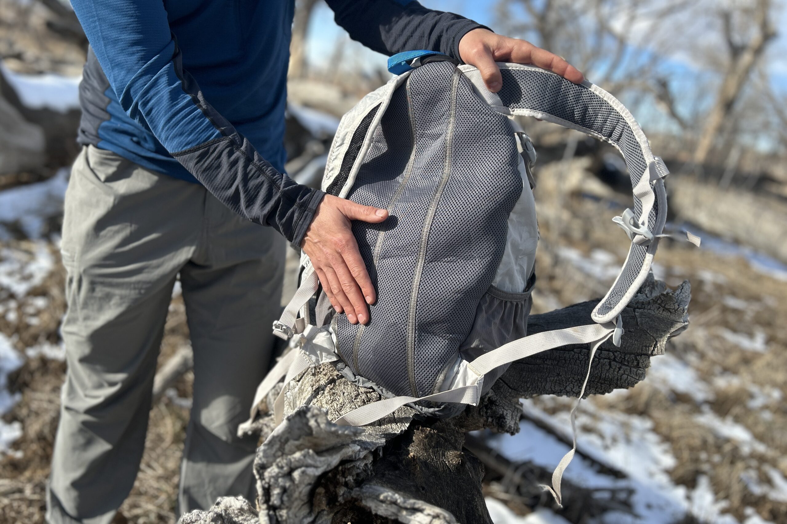 Close up of a person holding a backpack with their hand on the cushioned back.