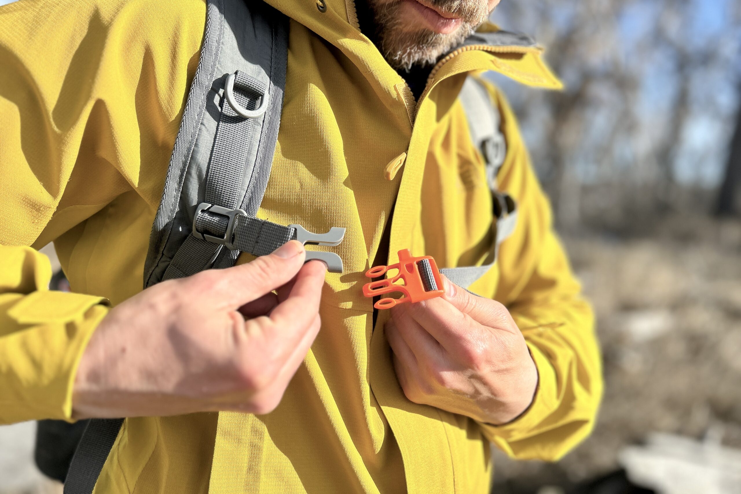 Closeup of a man buckling the sternum strap of a backpack.