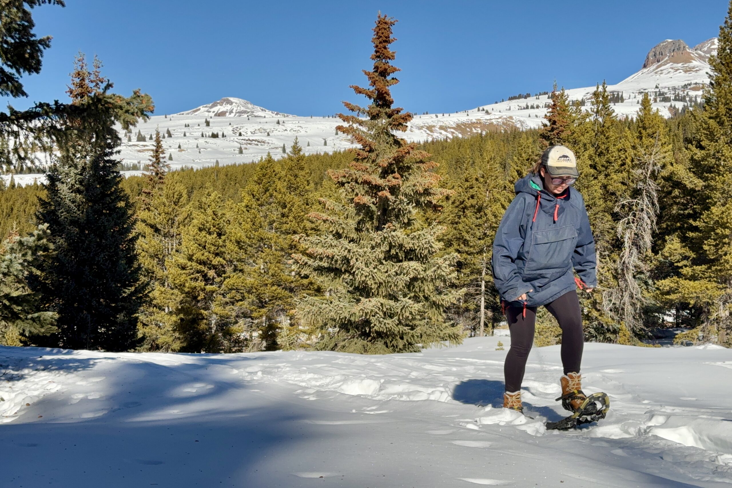 A person wearing the Bridger boots is snowshoeing in the mountains.