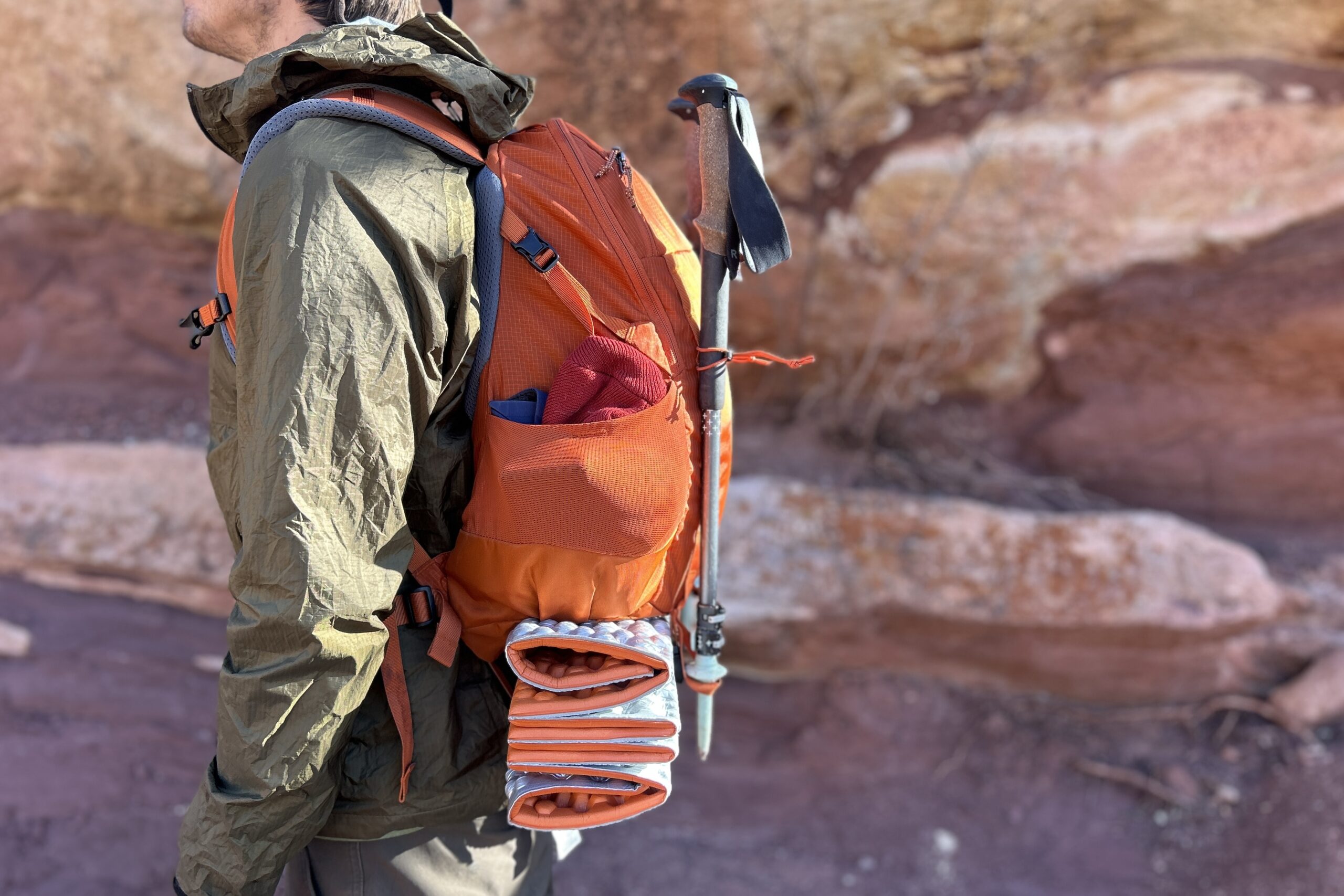 Closeup image of a man wearing a backpack from the side in a desert setting.