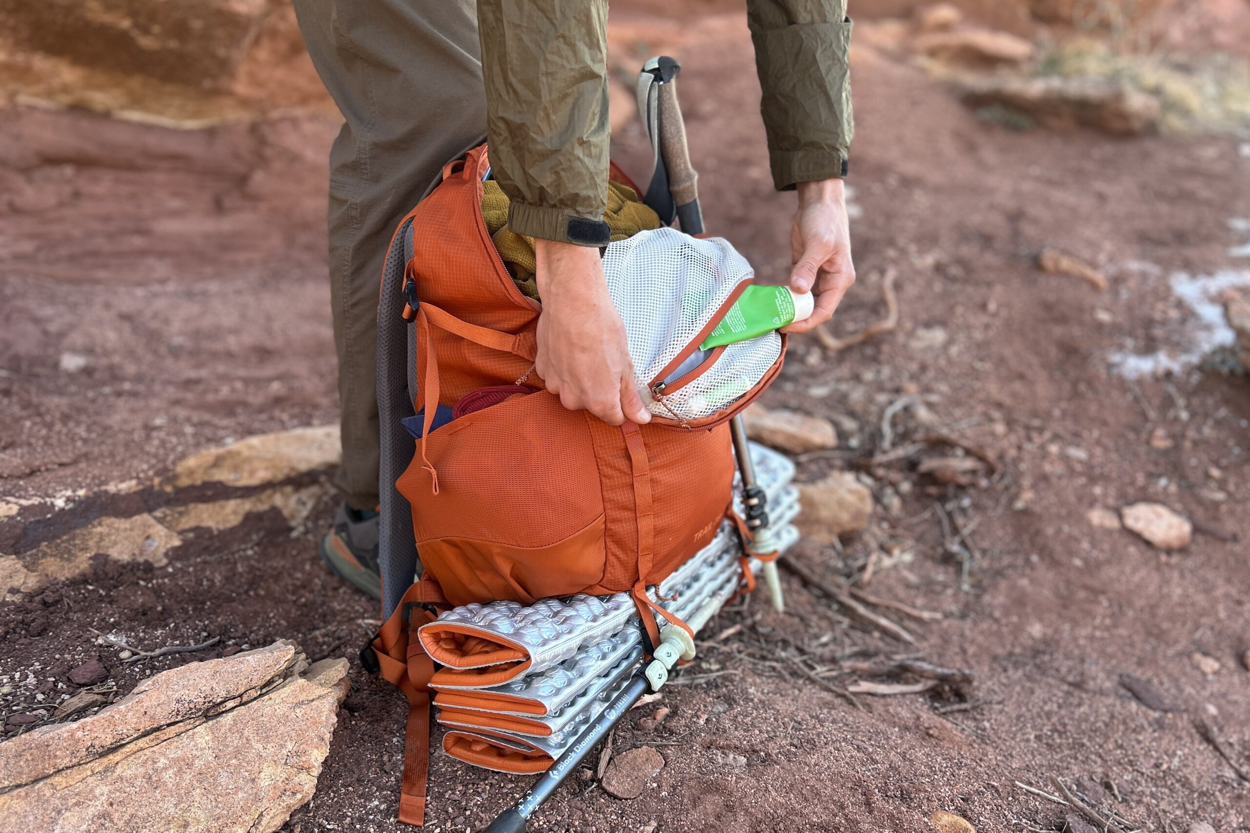 Closeup image of a a person pulling out the contents of their backpack from a pocket.