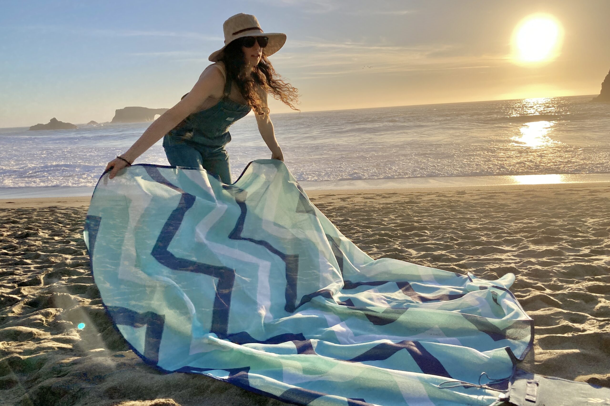 Woman laying the CGear Multimats Sandlite Sand-free Mat out on the beach.