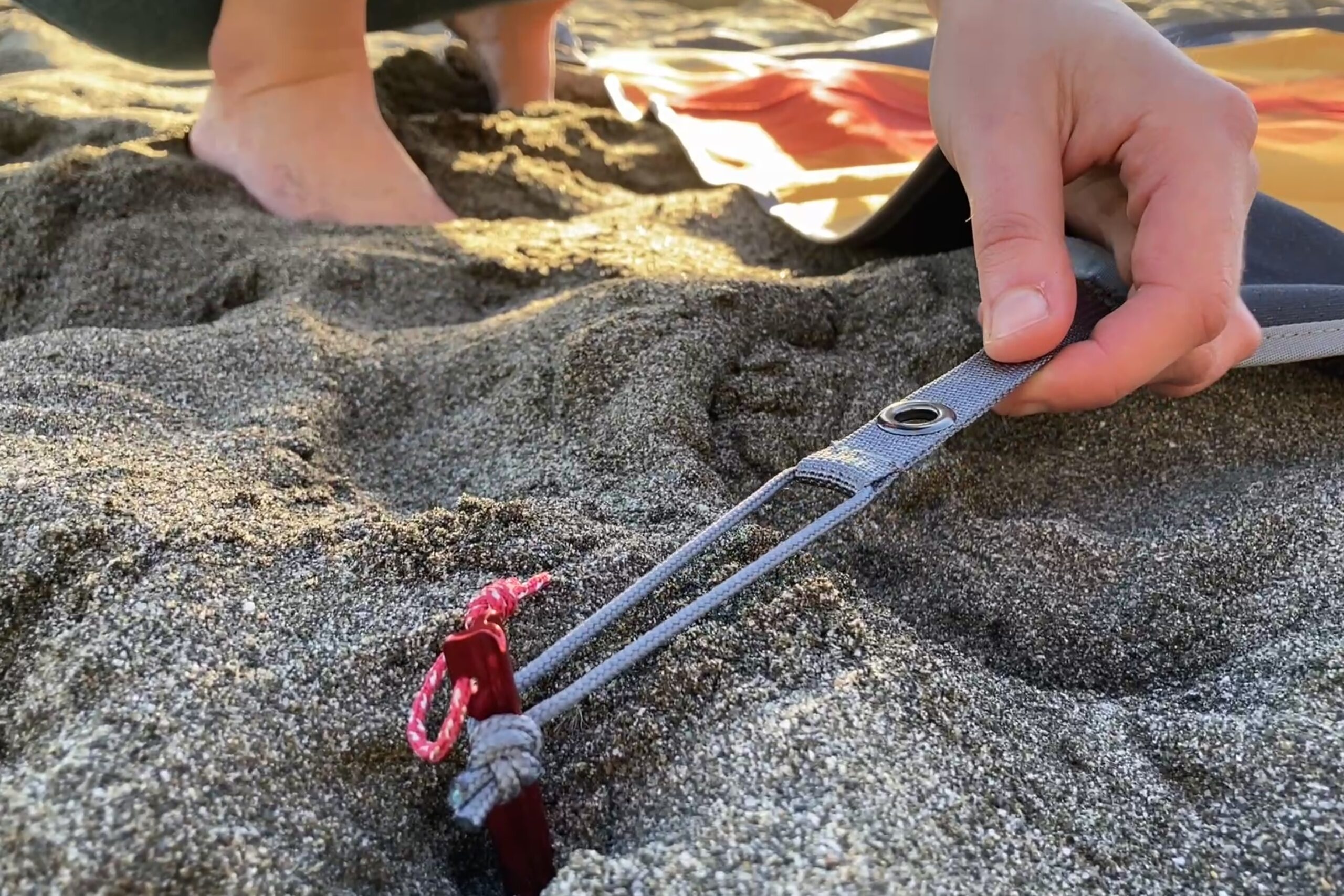 Showing a close-up of the corner loops on the Nemo Victory Patio Blanket in use with a tent stake.