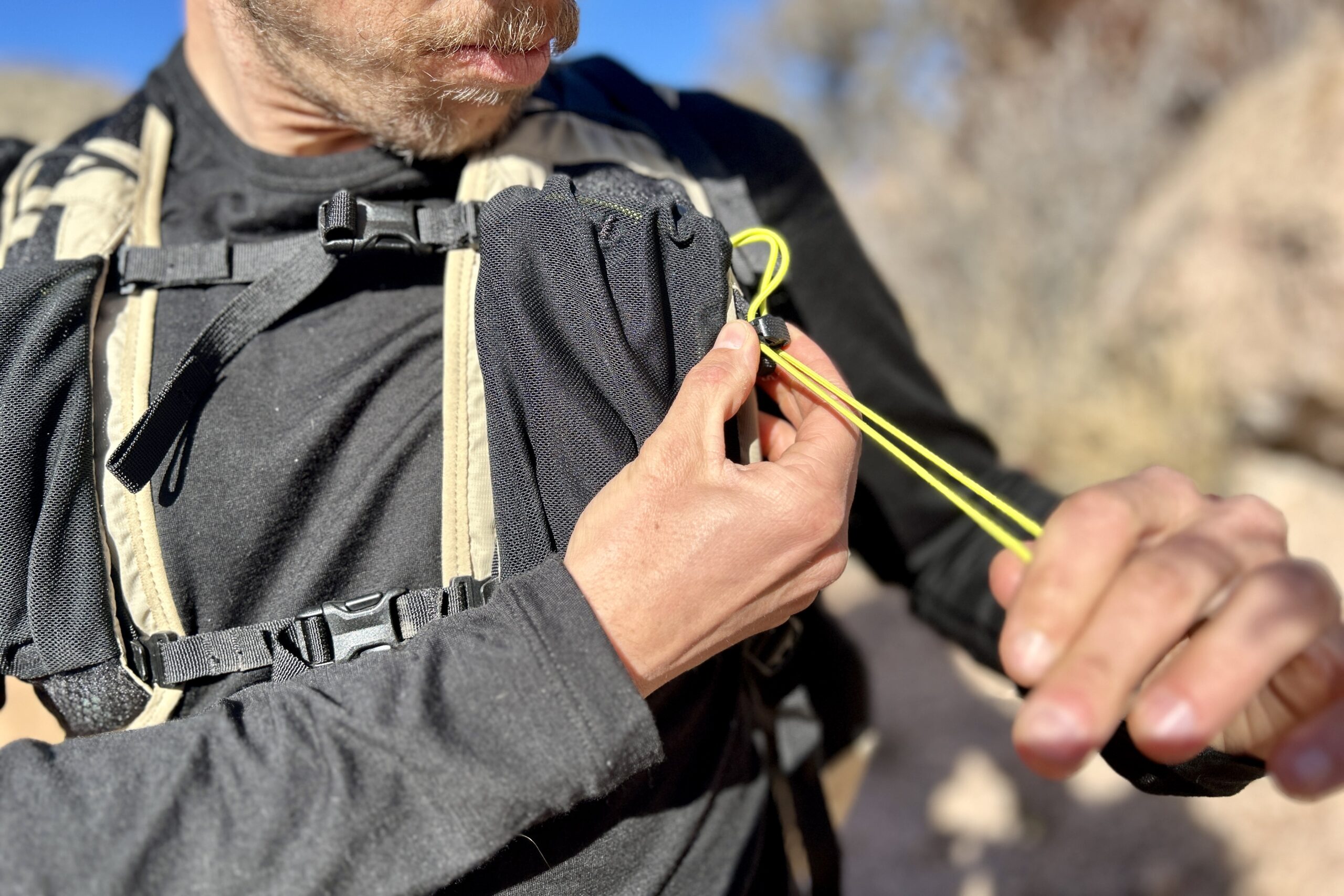 Close up of a man cinching a shoulder strap pocket closed.