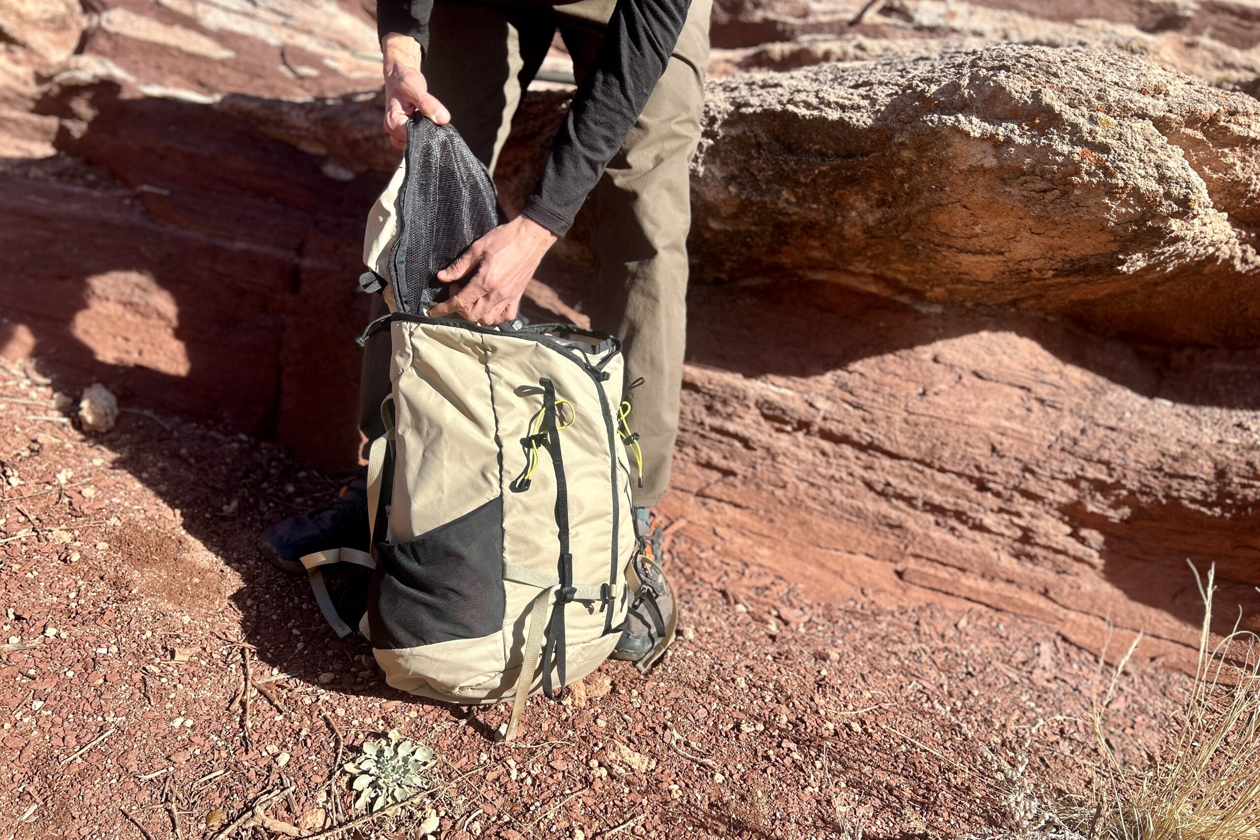 Close up of a person sifting through their backpack in a desert setting.