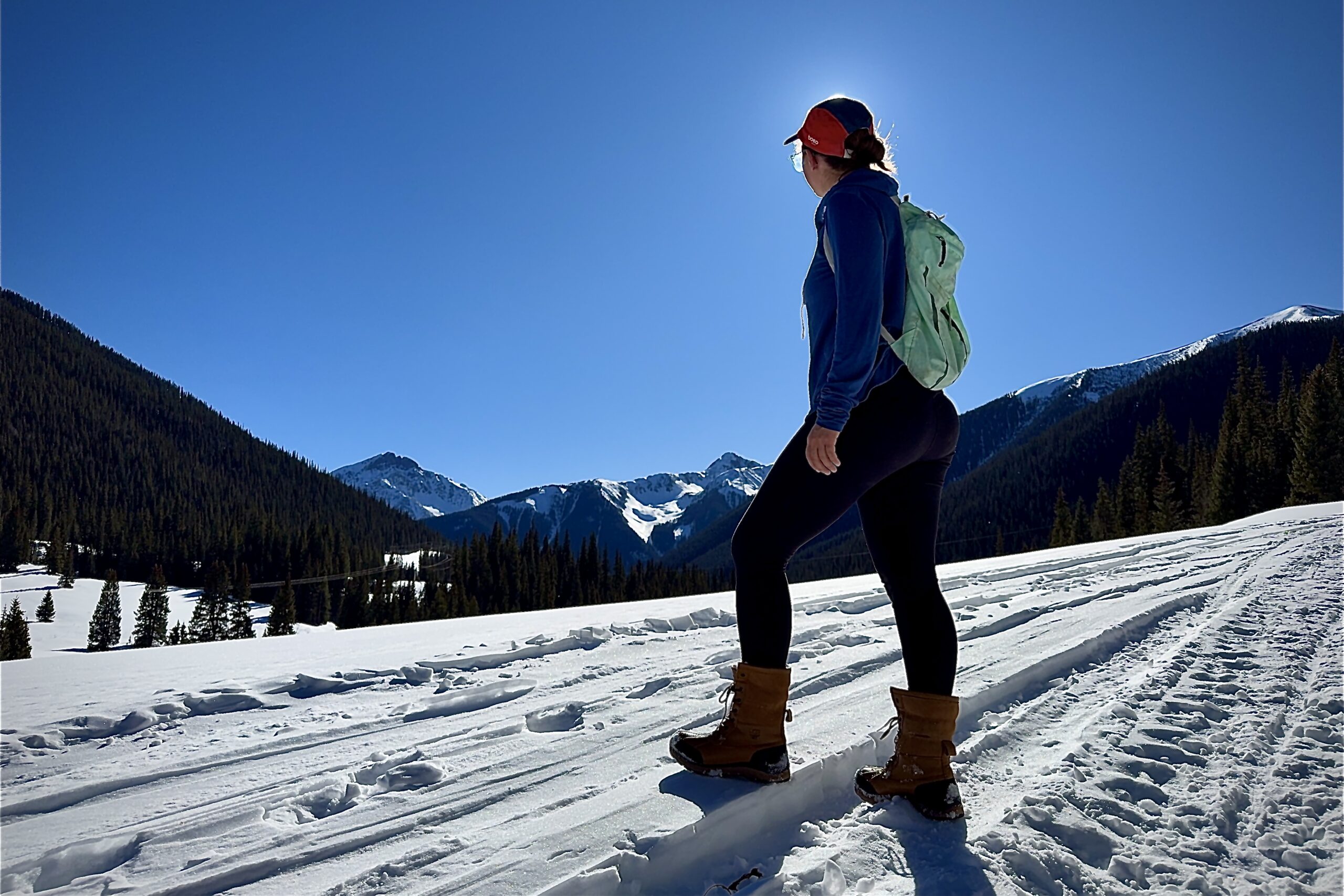 A person wearing the UGG boots is looking out at a snowy, mountain view.