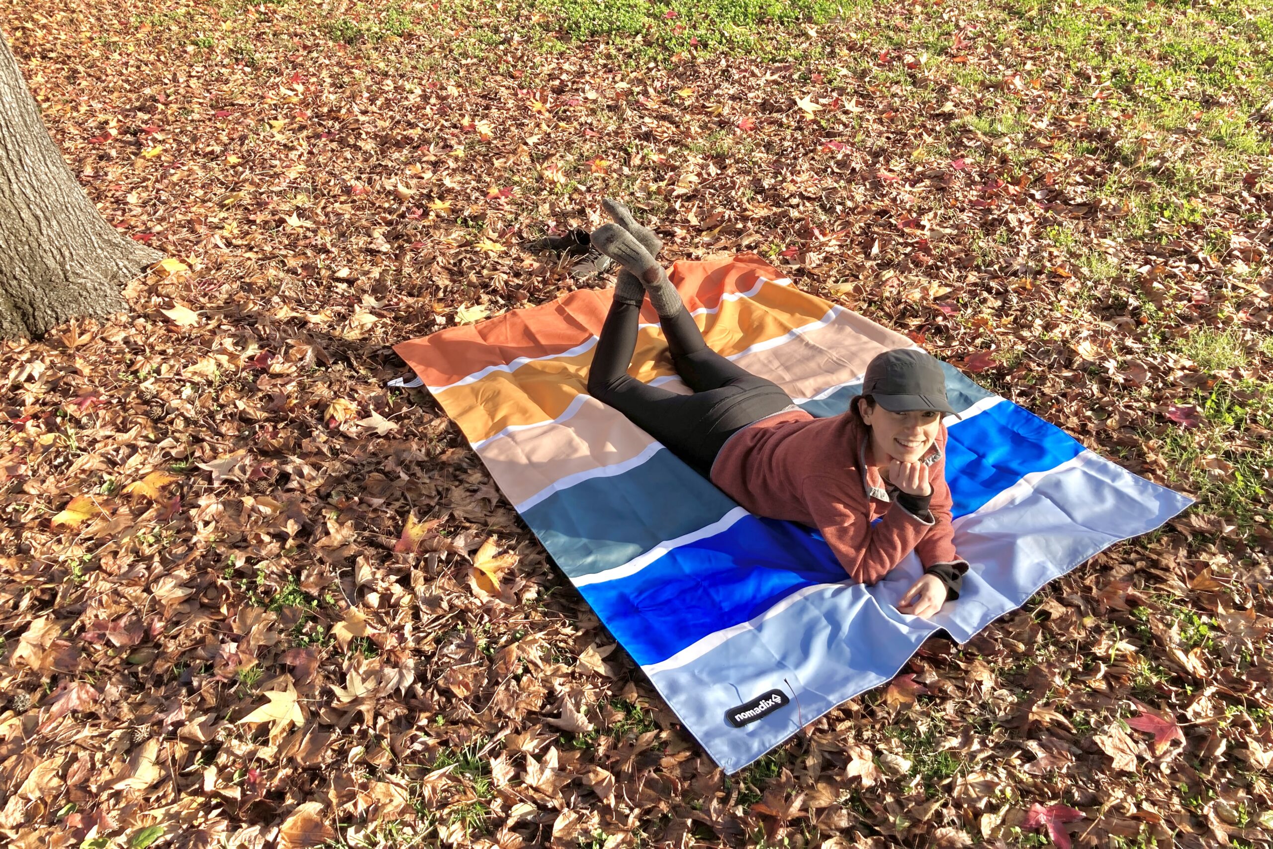 Women laying on her stomach under a tree in the Nomadix Festival Blanket