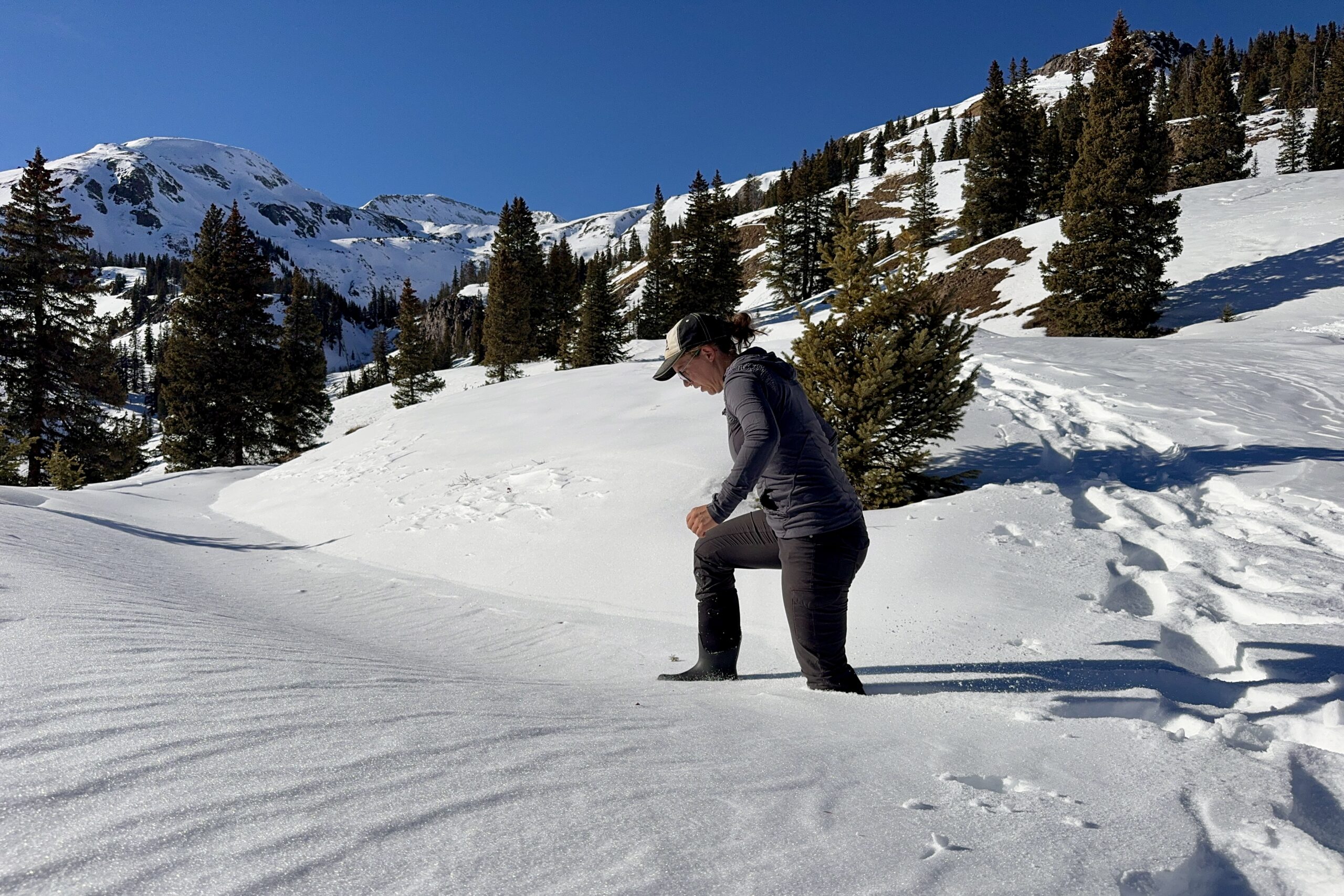 A person post-holing in snow while wearing the Neo Classic Tall boots in the mountains.