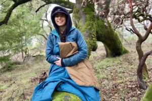 Women sitting on log with the REI camp blanket used as a throw over her legs